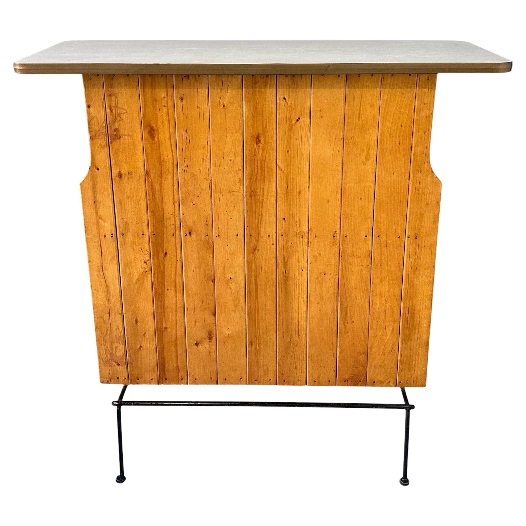Early dry bar by Arthur Umanoff made of birch and wrought iron. This bar has a white laminate top. and plenty of storage space in the back with many shelves. This bar comes with a bar stool that was originally purchased with the bar in the 50s.