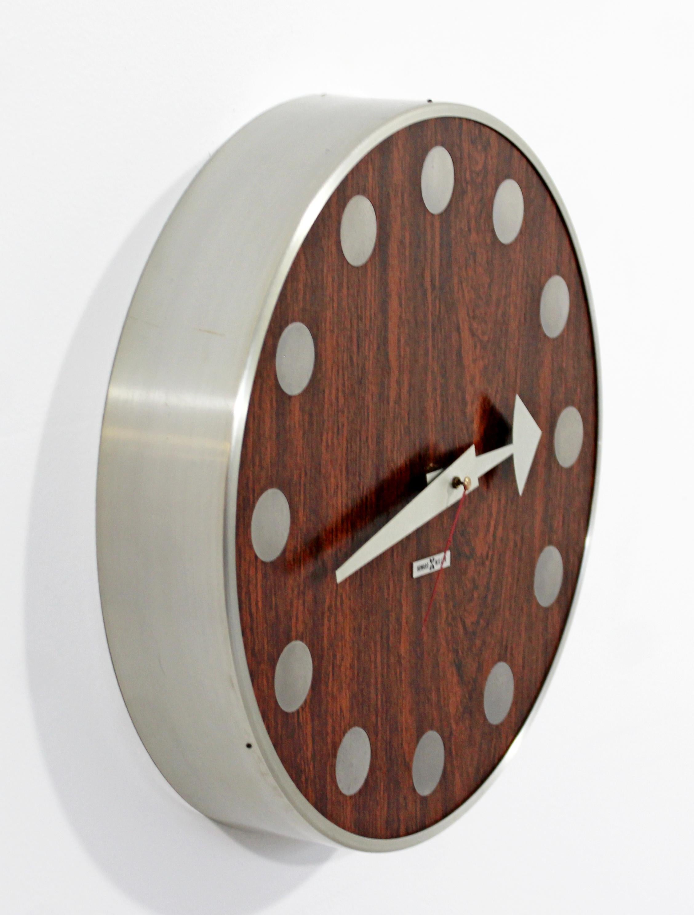 For your consideration is a warm and chic, round wall clock, made of chrome and with a rosewood face, by Arthur Umanoff for Howard Miller, circa 1960s. In excellent condition. The dimensions are 12.5