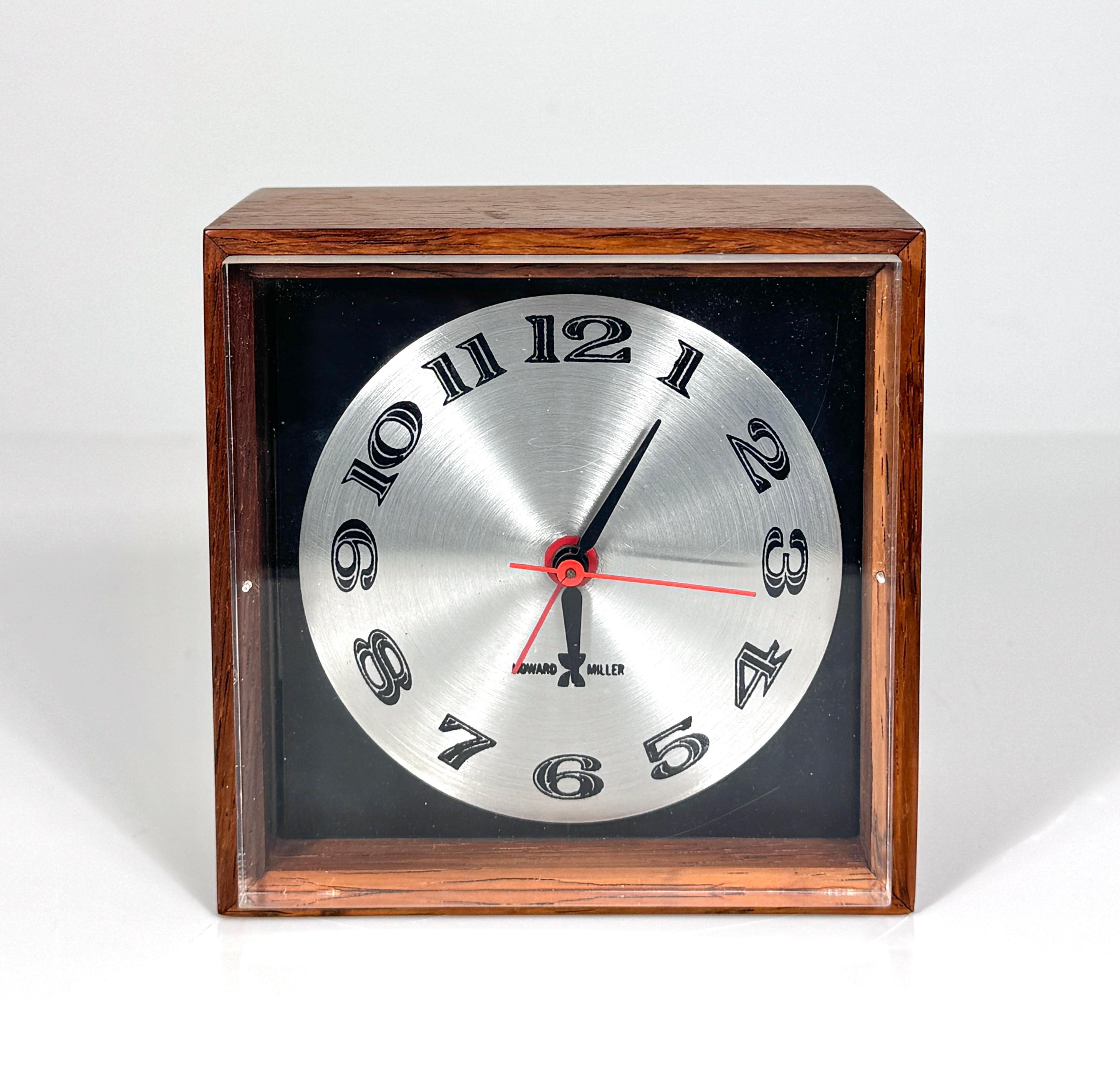 Arthur Umanoff model 645 alarm clock for Howard Miller circa late 1960s
Rosewood case with aluminum dial on a black background
Plug in electric movement with black hour and minute hands 
Red alarm set and sweeping second hand

Original label