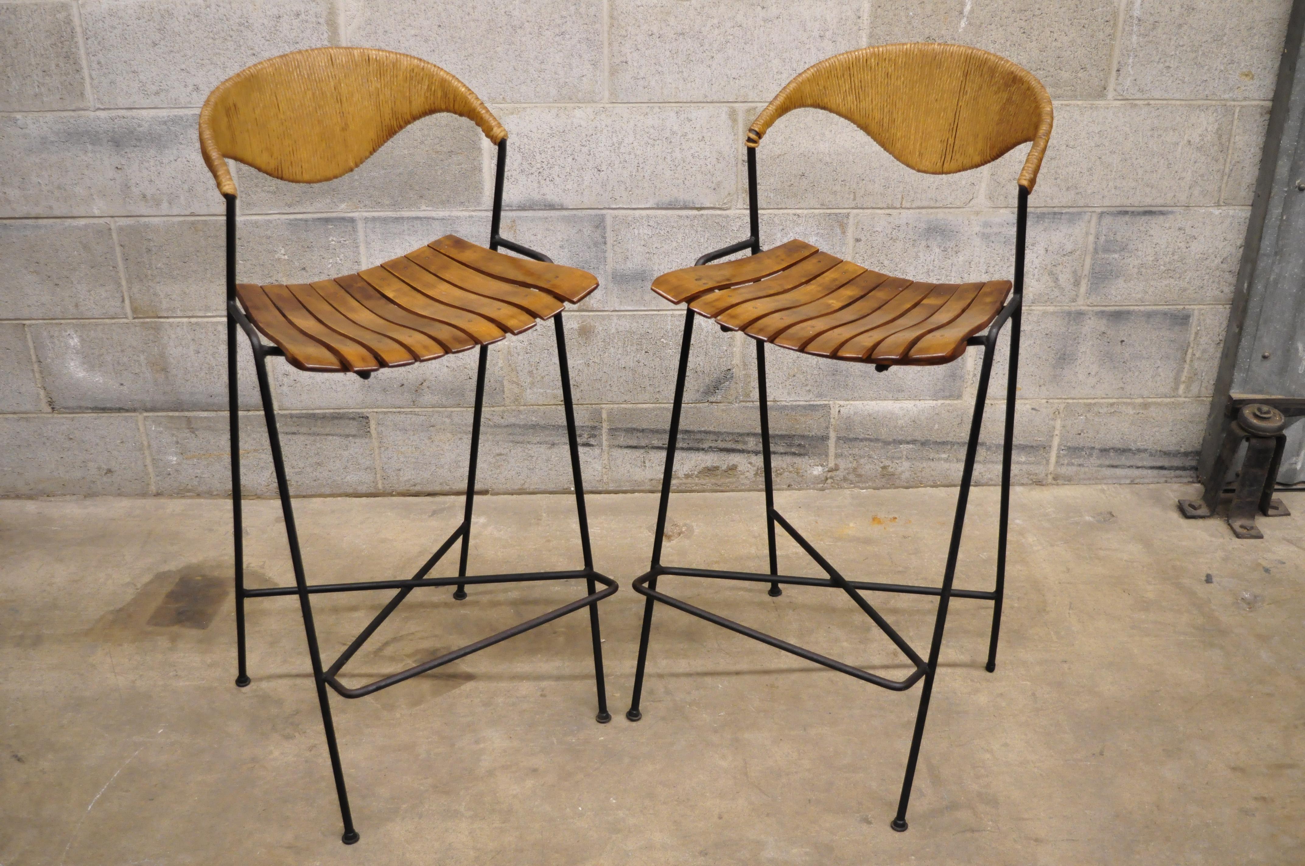 Mid-Century Modern Arthur Umanoff wrought iron and rattan bar and bar stools. Listing includes wrought iron frames, wood slat bar and seats, woven rattan backrests, laminate surface, (2) bar stools, (1) bar, very nice vintage item, great style and