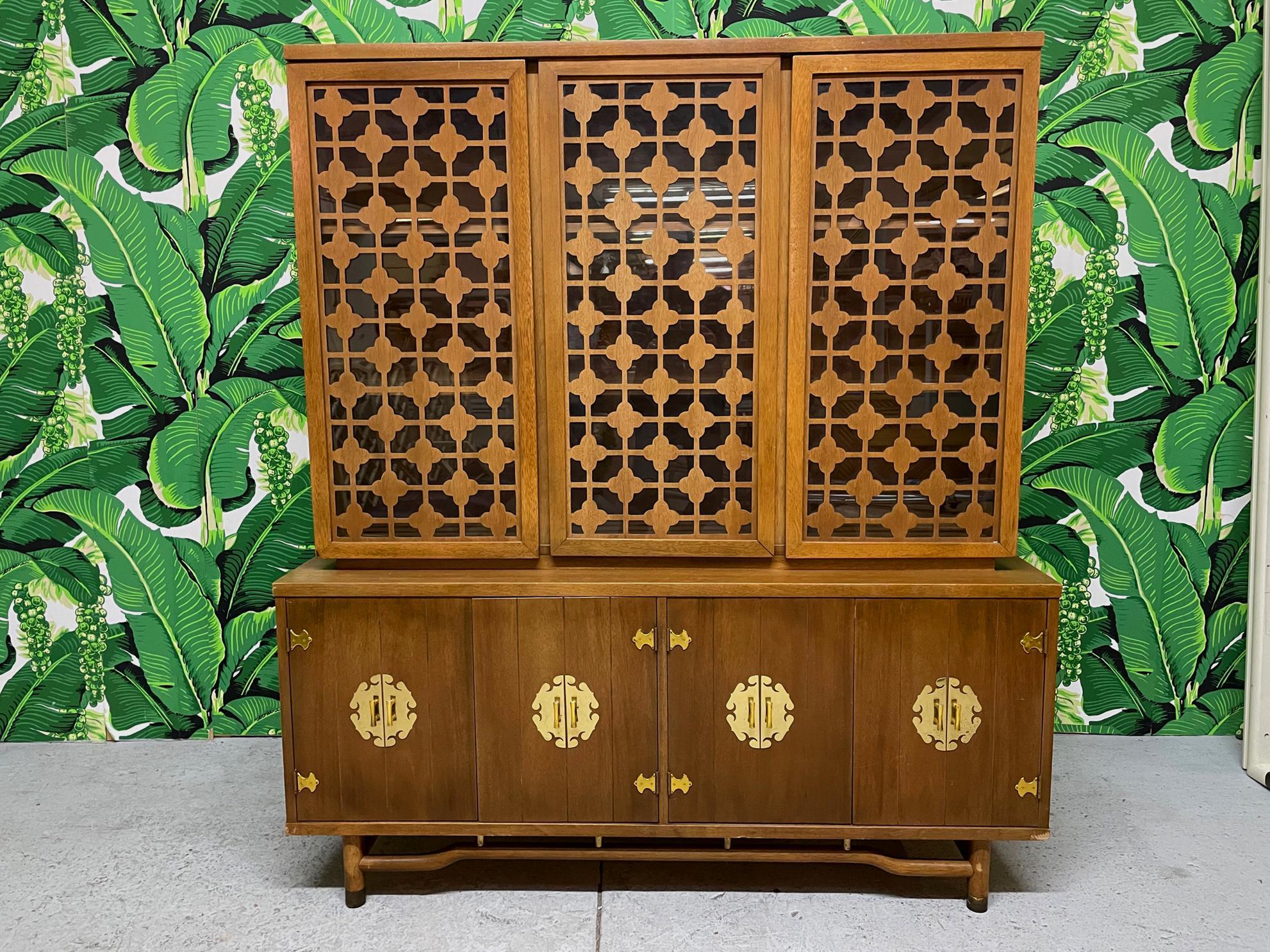 Mid-Century Modern style china cabinet features rattan style legs and brass asian chinoiserie style hardware. Good condition with minor imperfections consistent with age. May exhibit scuffs, marks, or wear, see photos for details.

 