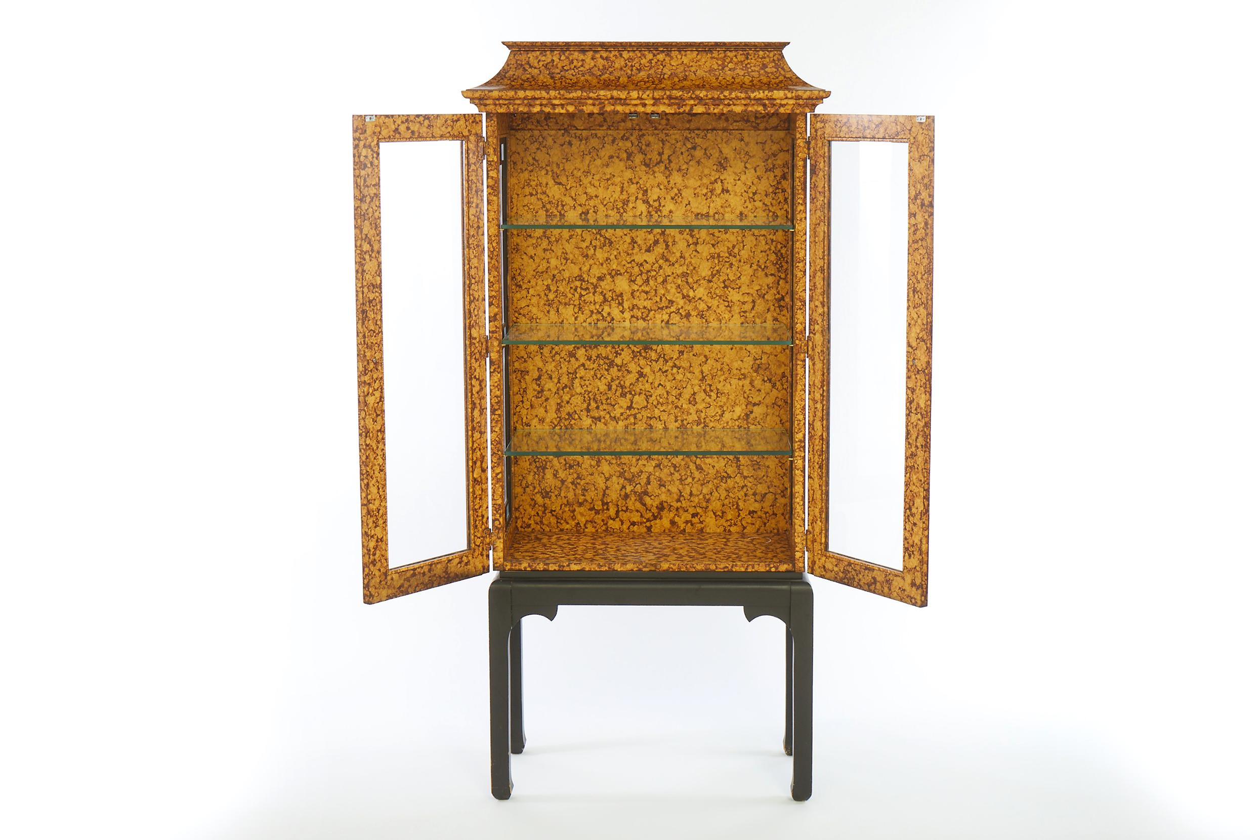Mid-Century Modern Asian style faux finished display cabinet / vitrine with pagoda style top and ebonized base featuring inside glass shelves with double brass pull door. The cabinet / vitrine is in good condition with appropriate wear consistent
