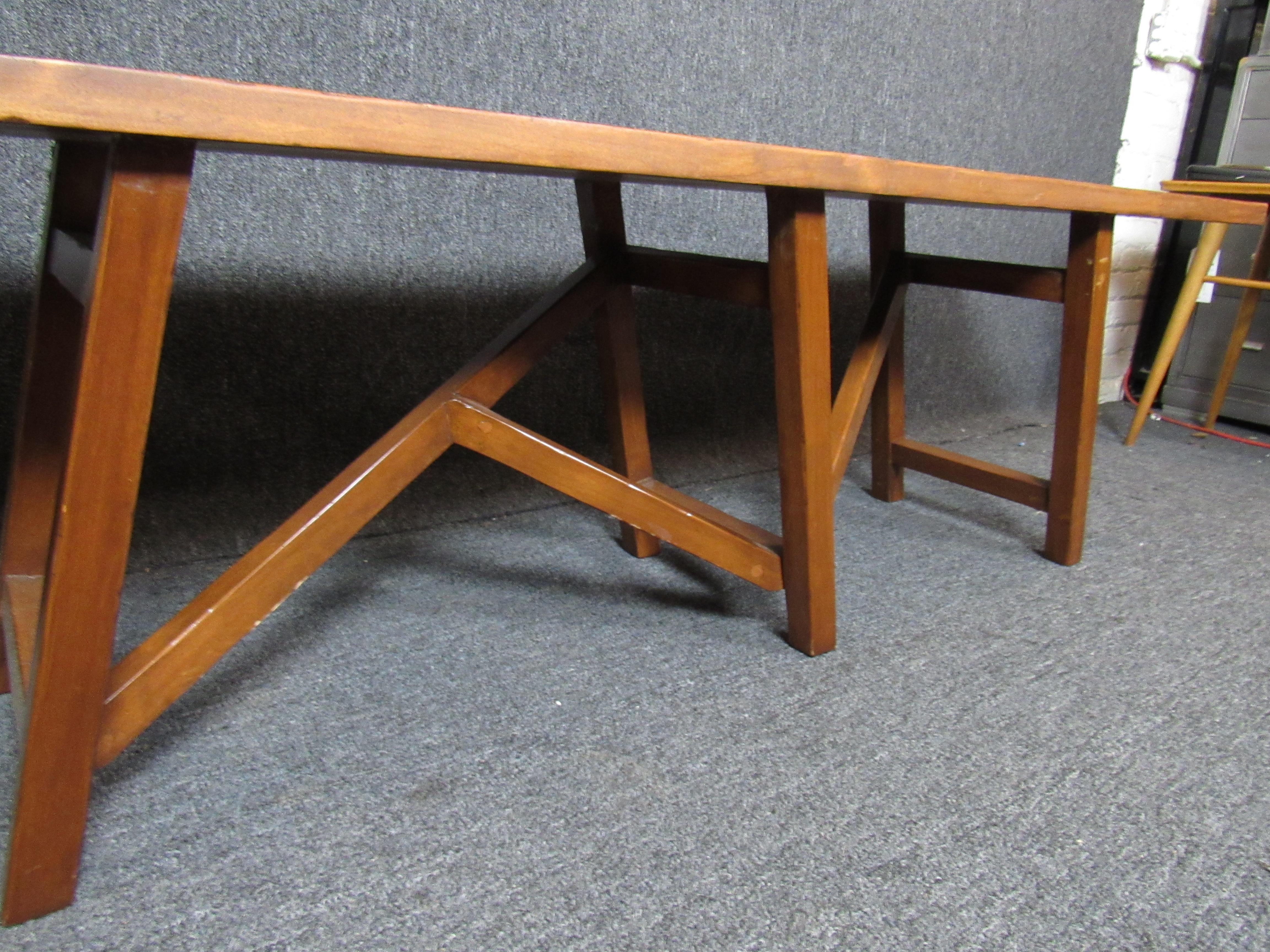 Terrifically wonderful mid-century bench with a unique asymmetrical leg design. Large top shows off a nice, warm grain as well as joint details. Extremely versatile piece perfect for the home or office, as a seat or table. 

(Please confirm item