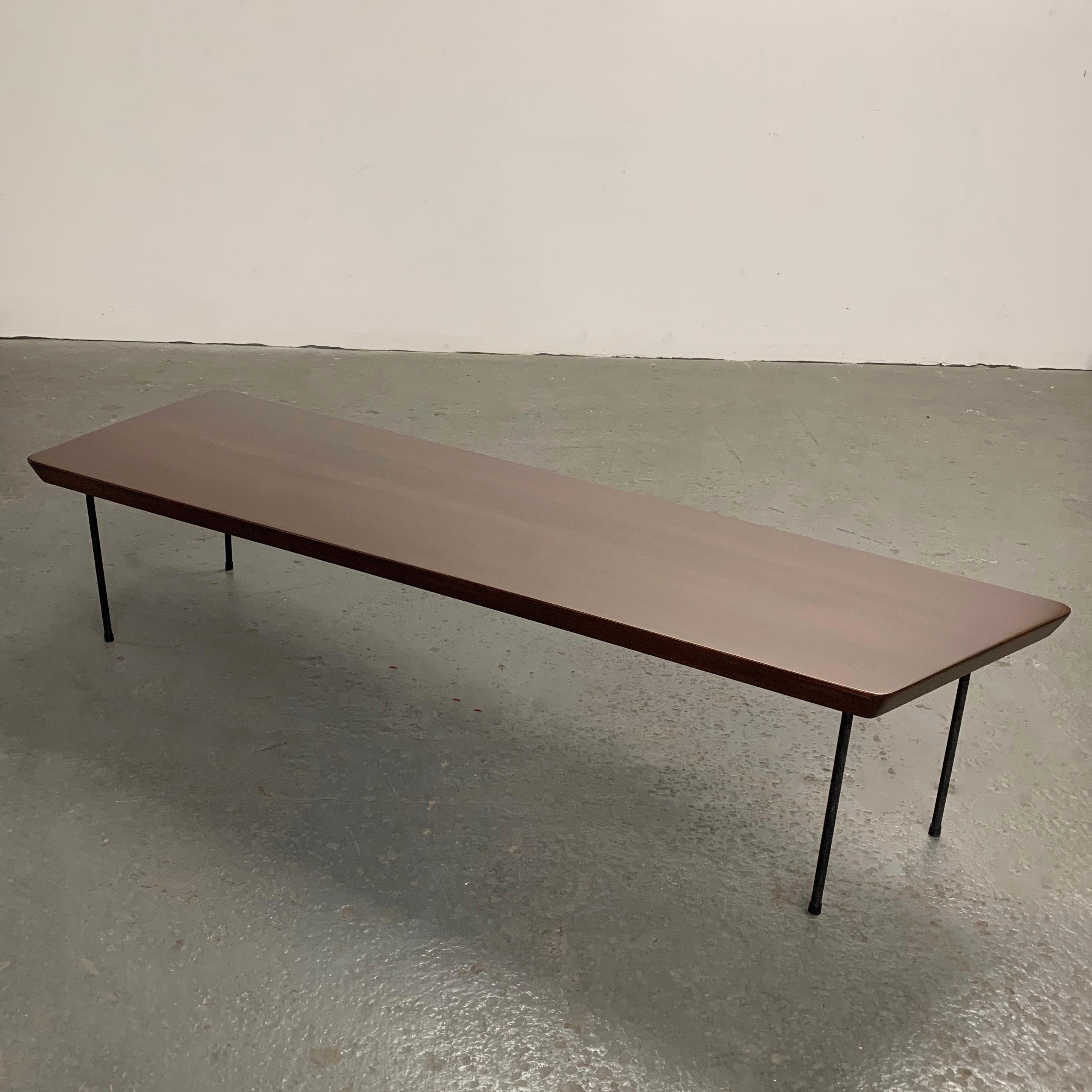 Mid-Century Modern coffee table features a solid maple, asymmetrically shaped top with beveled edges and wrought iron legs. The top tapers from 66 inches x 22 inches to 56 inches x 16 inches wide.