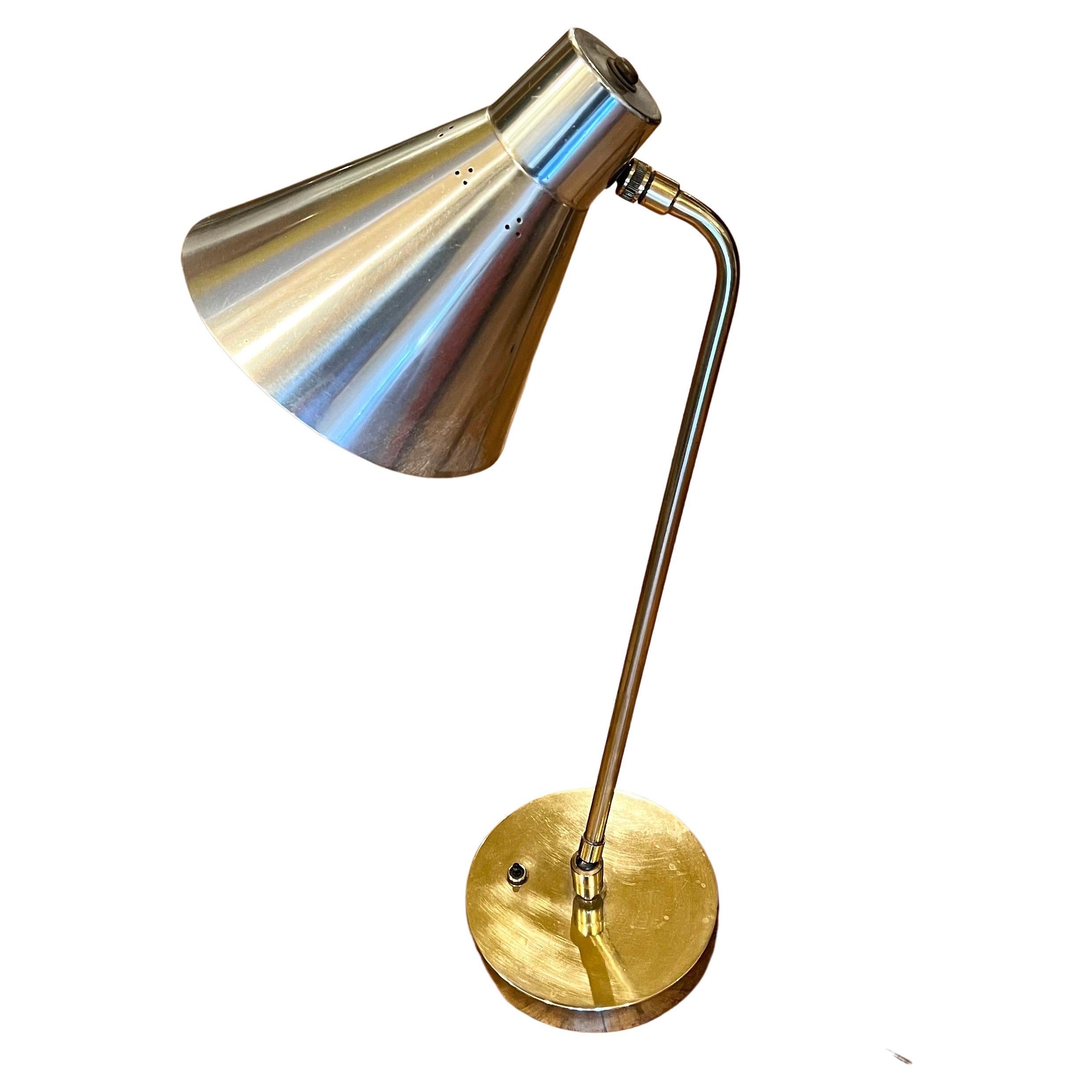 Beautiful and rare multidirectional brass desk top lamp with polished aluminum shade and solid polished brass arm and base with great quality brass adjusters that makes it variable to adjust in many positions.