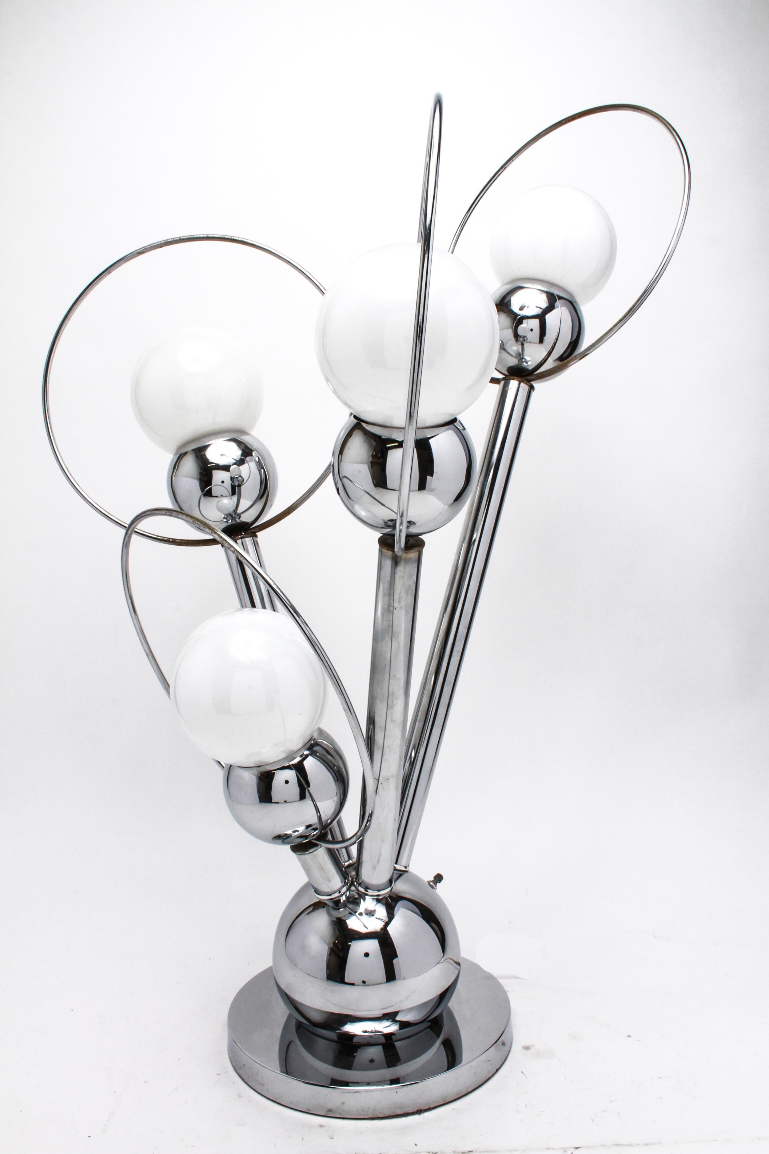 Mid-Century Modern atomic era Sputnik table lamp in chromed metal with four arms having dome ends with globe bulbs, encircled by large rings. The piece is in great vintage condition with some minor chrome wear to the rings.