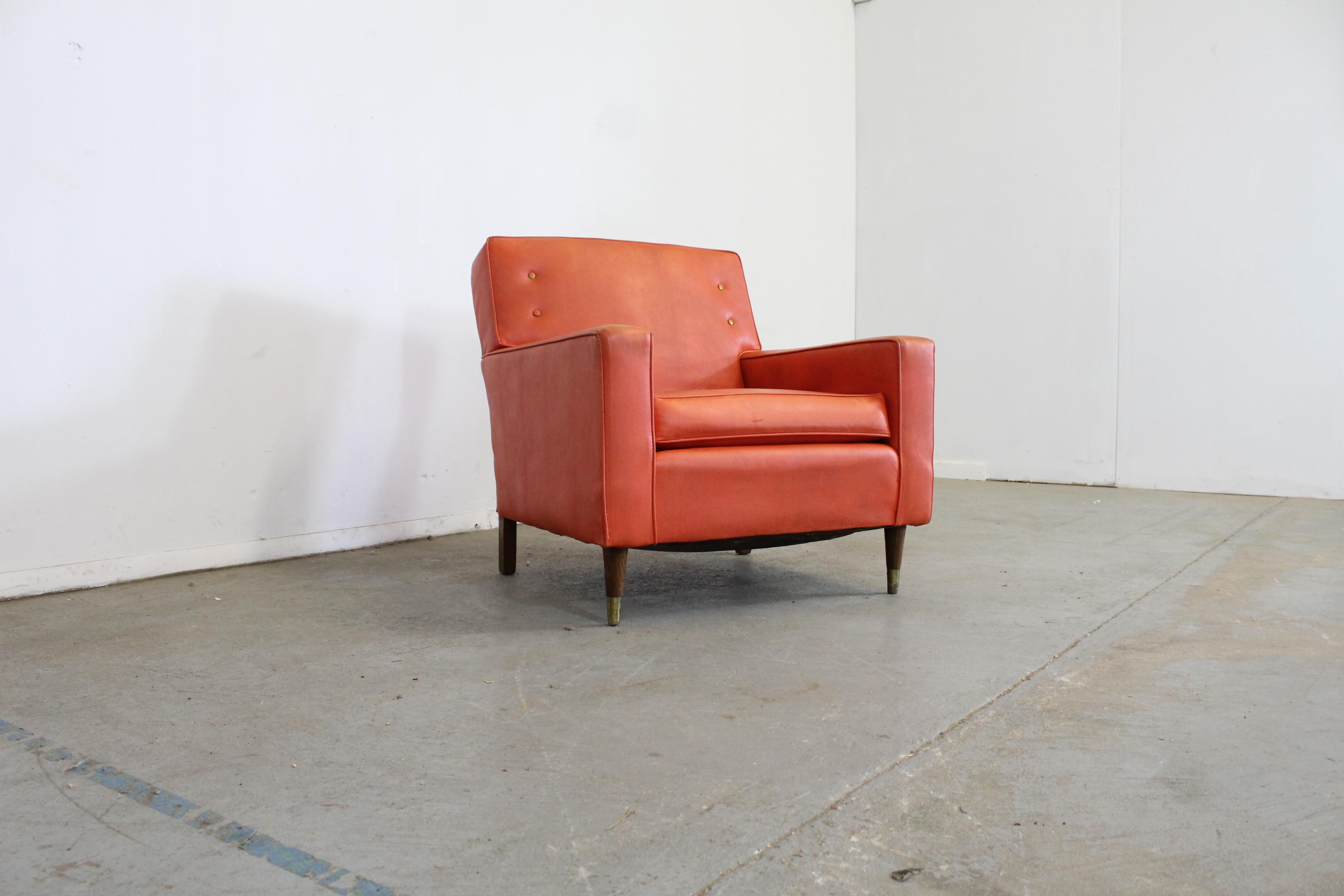 Mid-Century Modern atomic orange club chair on pencil legs

Offered is a vintage mid-century modern chair. It is on walnut legs. It is not signed. It features an atomic orange vinyl. It needs to be reupholstered as there is significant tearing and