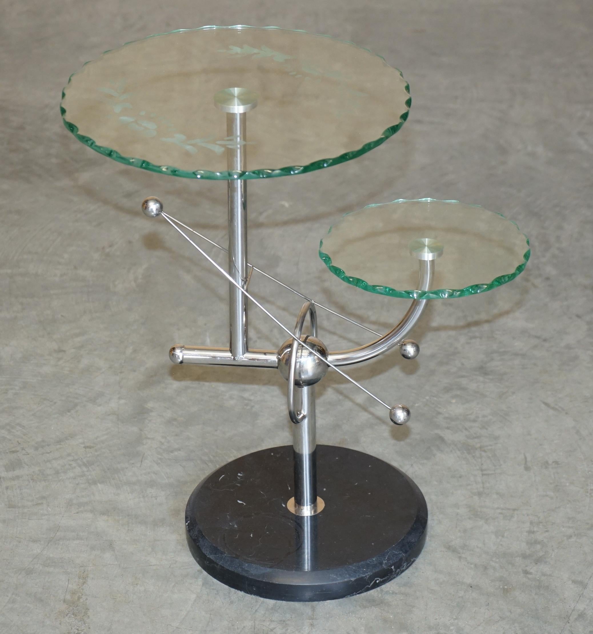 Nous sommes ravis de proposer à la vente cette superbe table d'appoint chromée, de style moderne du milieu du siècle dernier, de l'ère spatiale atomique, avec des plateaux en verre gravé et des bases en marbre épais 

Une pièce très belle et bien