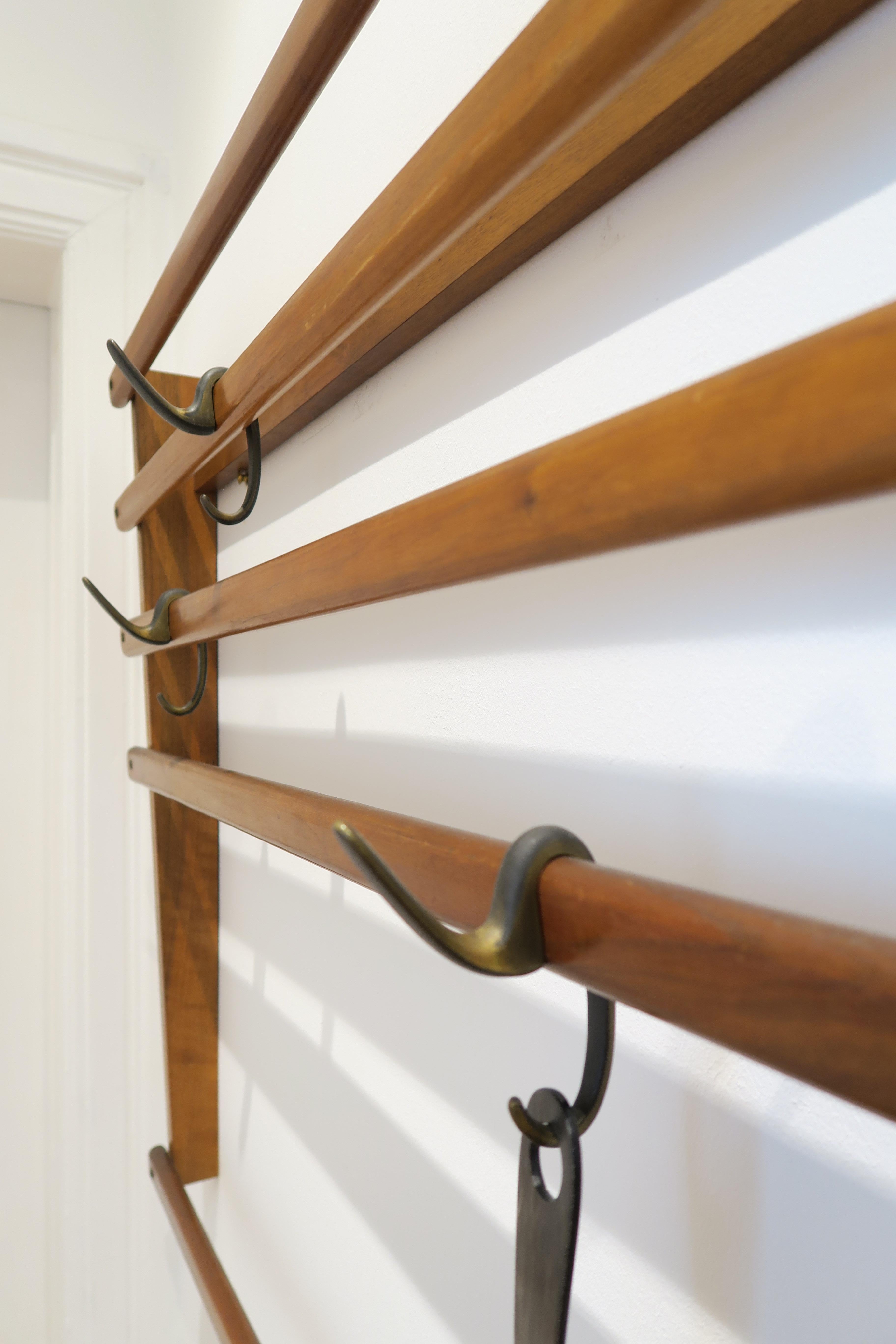 For sale is an original Mid-Century Modern piece of design. The coat rack consists of beautiful warm nutwood with four brass hooks. The wooden slats have been assembled with raised countersunk brass screws. Both materials have gained a nice patina