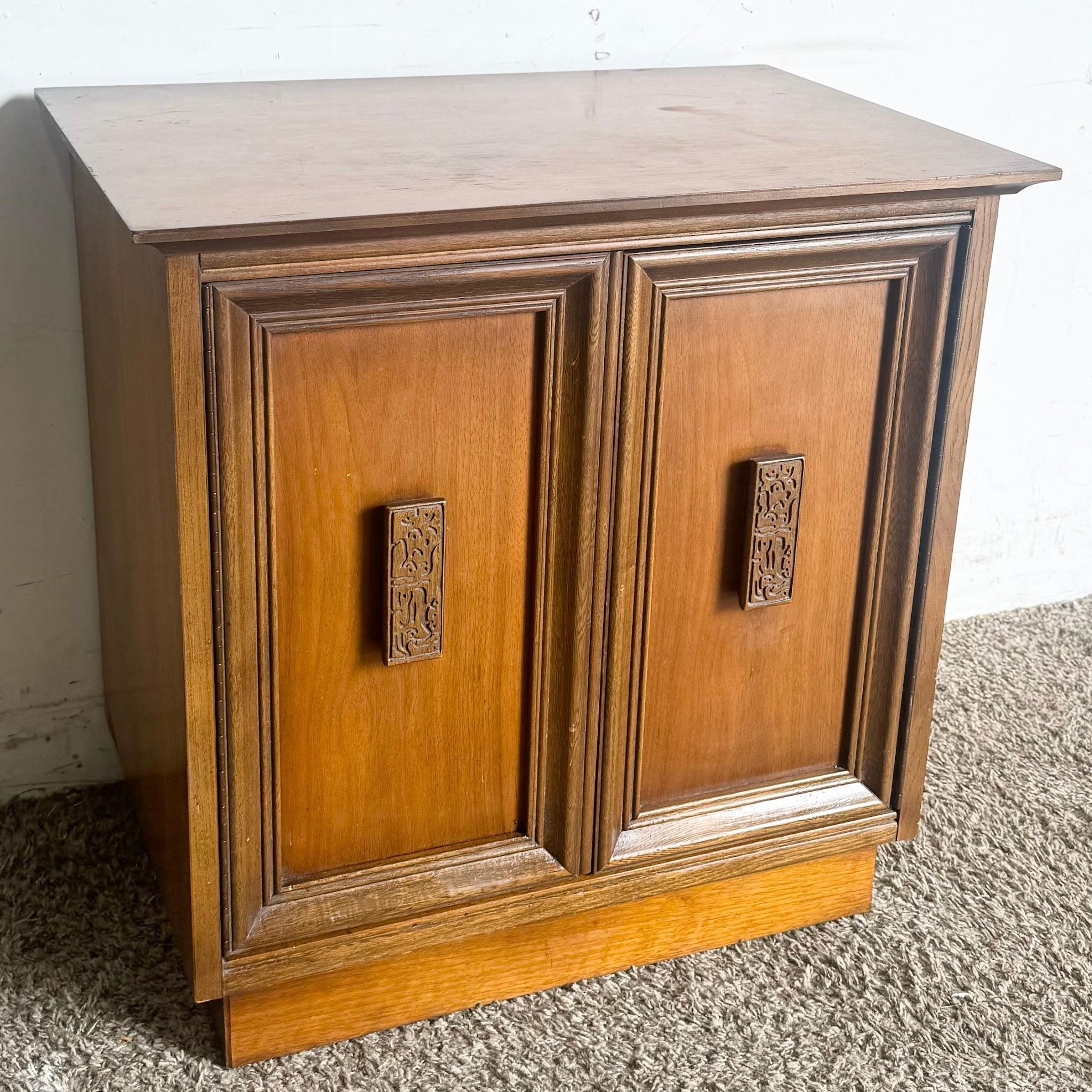 This Mid Century Modern Mayan nightstand by Basset features a striking geometric design and rich wood finish, perfect for adding a touch of vintage charm to any bedroom. Its compact size and single drawer provide both style and functionality.
