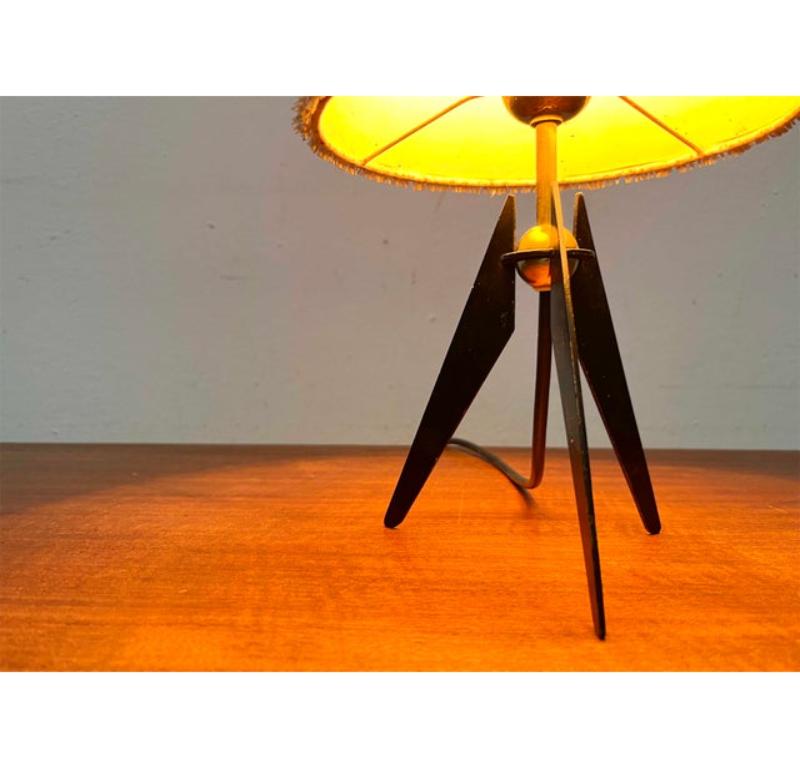 Small tripod table lamp of Austrian origin from the 60s.

An elegant lamp that is based on Carl Auböck's design language. The shade is conical and covered on the outside with a bast-like material. The striking fringe structure creates a diffuse