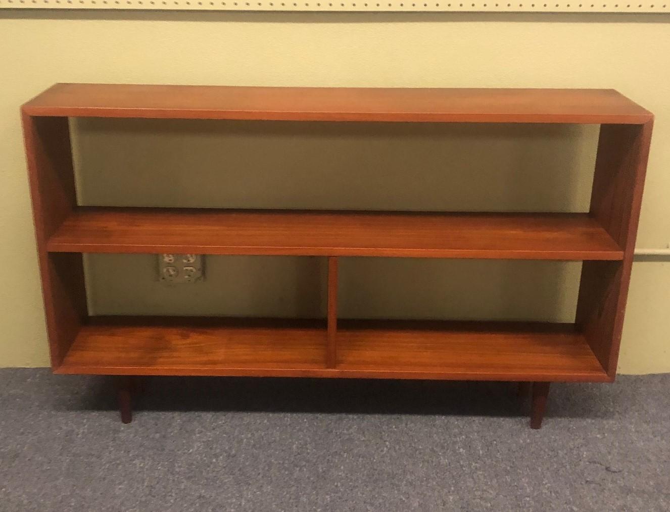 Mid-Century Modern backless low profile teak bookcase with tapered legs, circa 1960s. Wonderful wood grain and color! A very practical piece for a number of different spaces, can also be used as a room divider as it is finished on both sides.