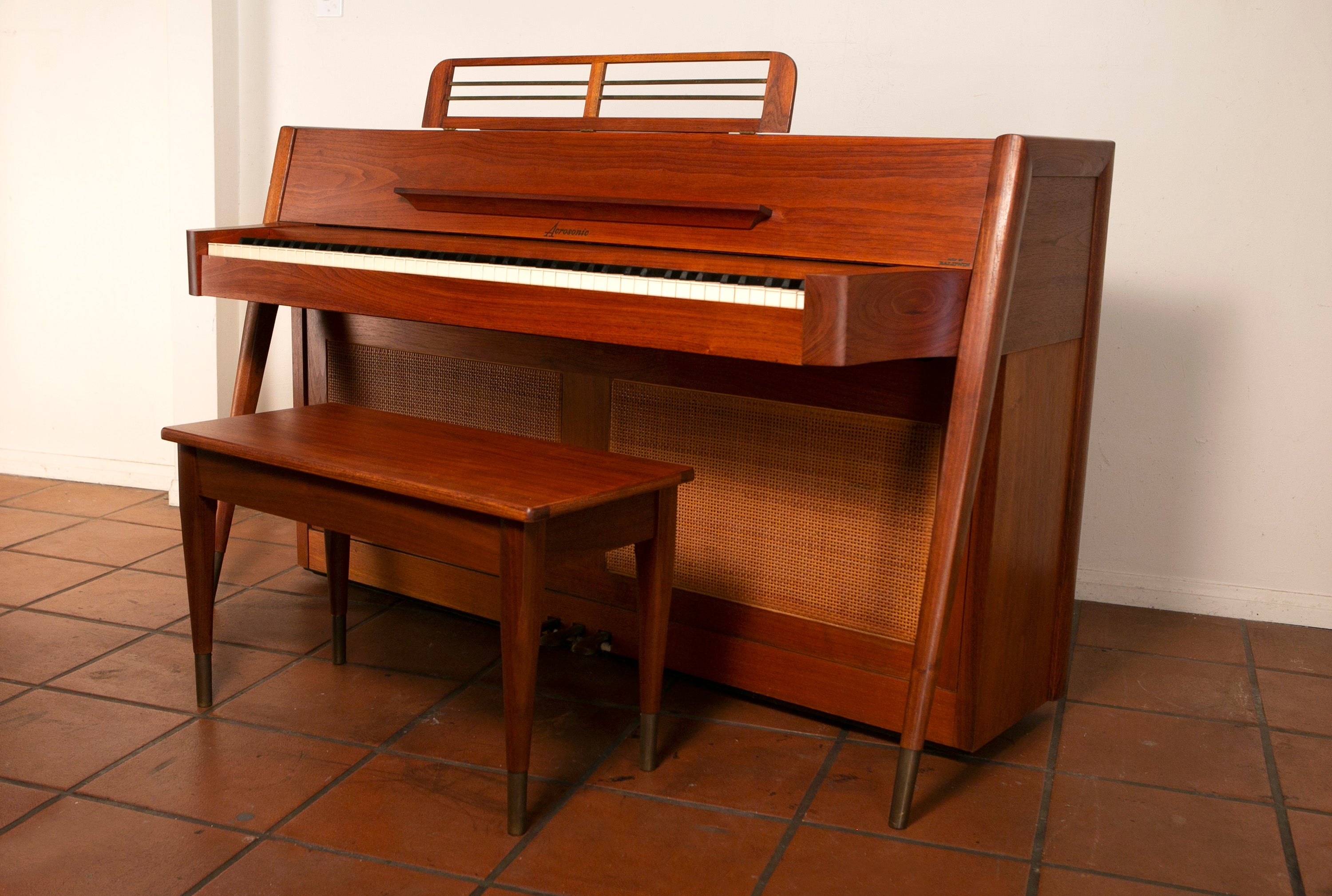 Mid-Century Modern Baldwin Acrosonic Piano with bench in Walnut + Caning, 1960s

This Mid-Century Modern Acrosonic spinet piano made by Baldwin is very sought after and is an amazing addition to any home. It's signature Danish style modern tapered