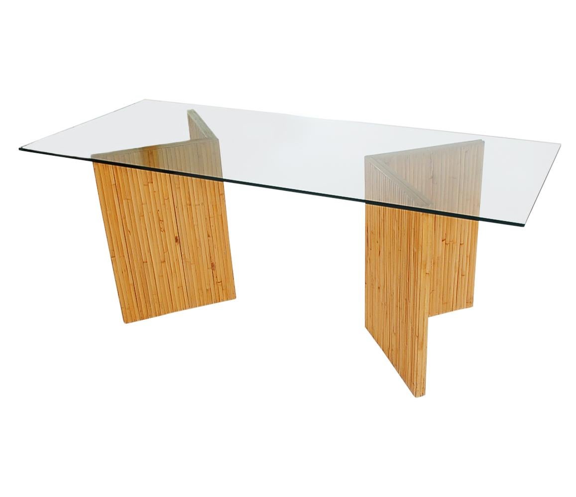 A stylish and versatile bamboo reed decorator table. Can be used as a console table or desk. It features two bamboo pedestals with thick clear glass top.