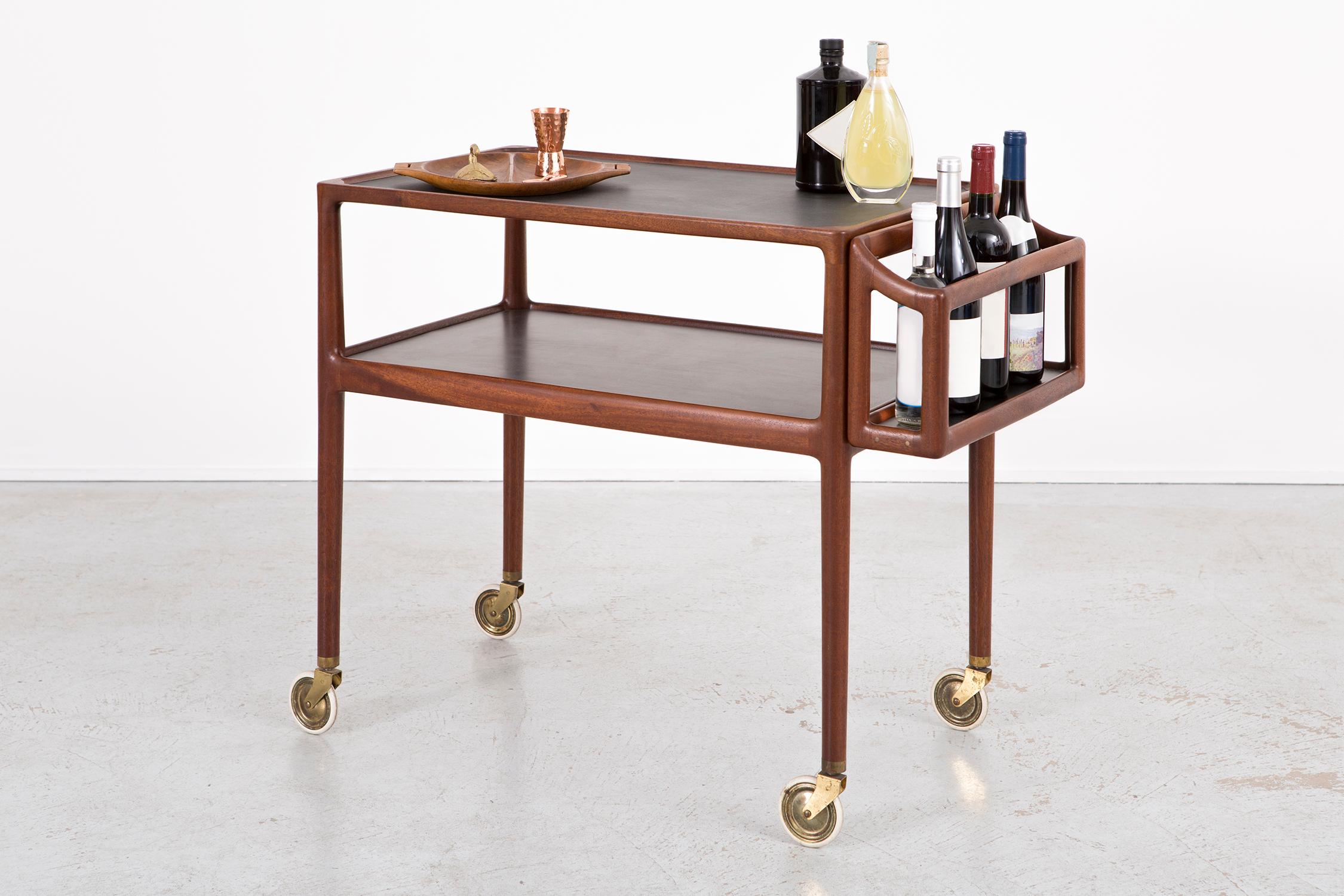 Bar cart

Attributed to Poul Hundevad

Denmark, circa 1960s

Wood and micarta

Measures: with caddy 27 15/16” H x 18 ½” W x 35 3/16” D

Without caddy 27 15/16” H x 18 ½” W x 30 ?” D.

Caddy comes off, creates for a very versatile bar