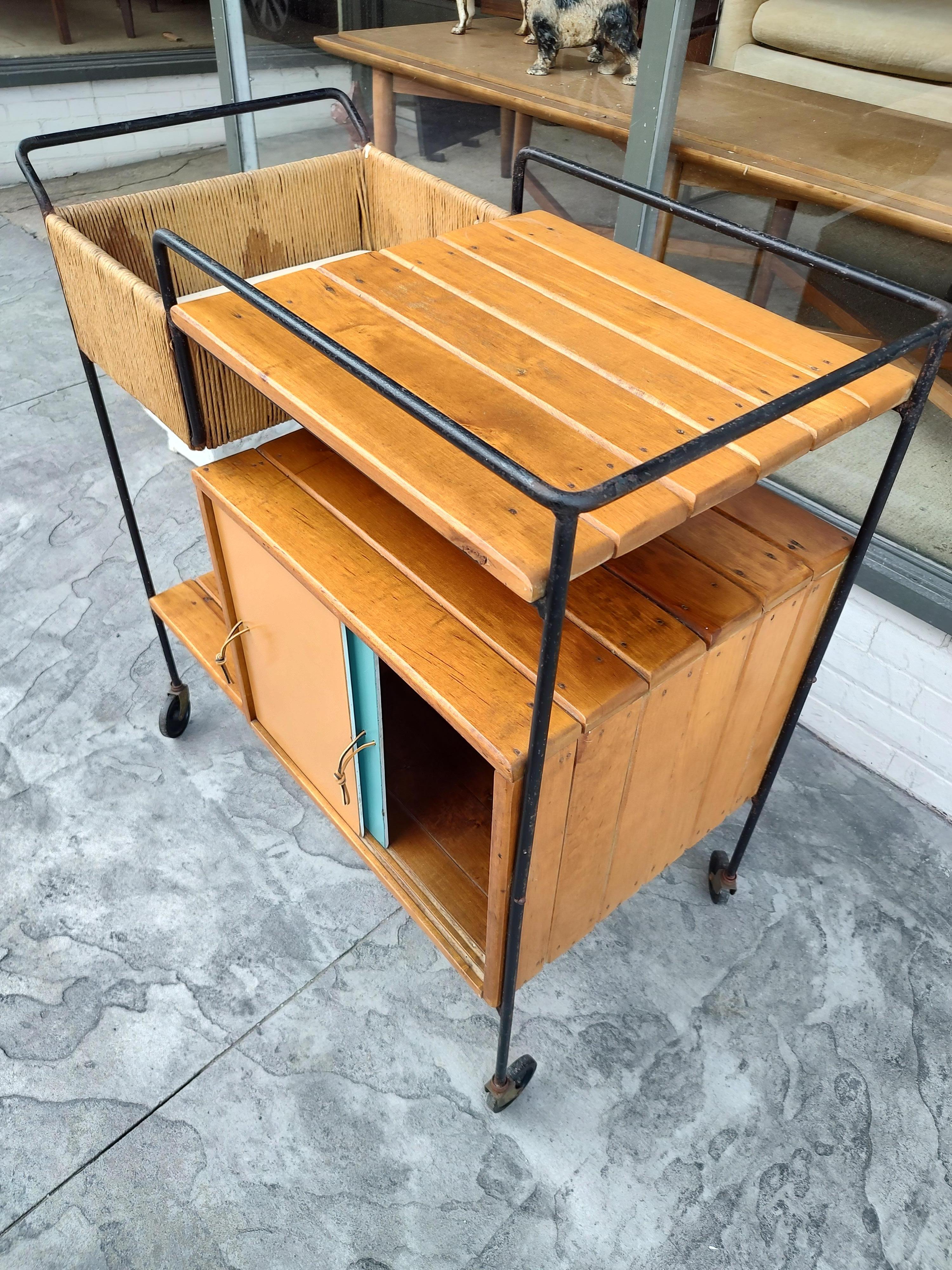 Fabulous bar cart by Arthur Umanoff for Raymor. Hand forged iron with Raffia and Maple. Sliding doors on both sides with new leather pulls. In excellent vintage condition with minimal wear.
