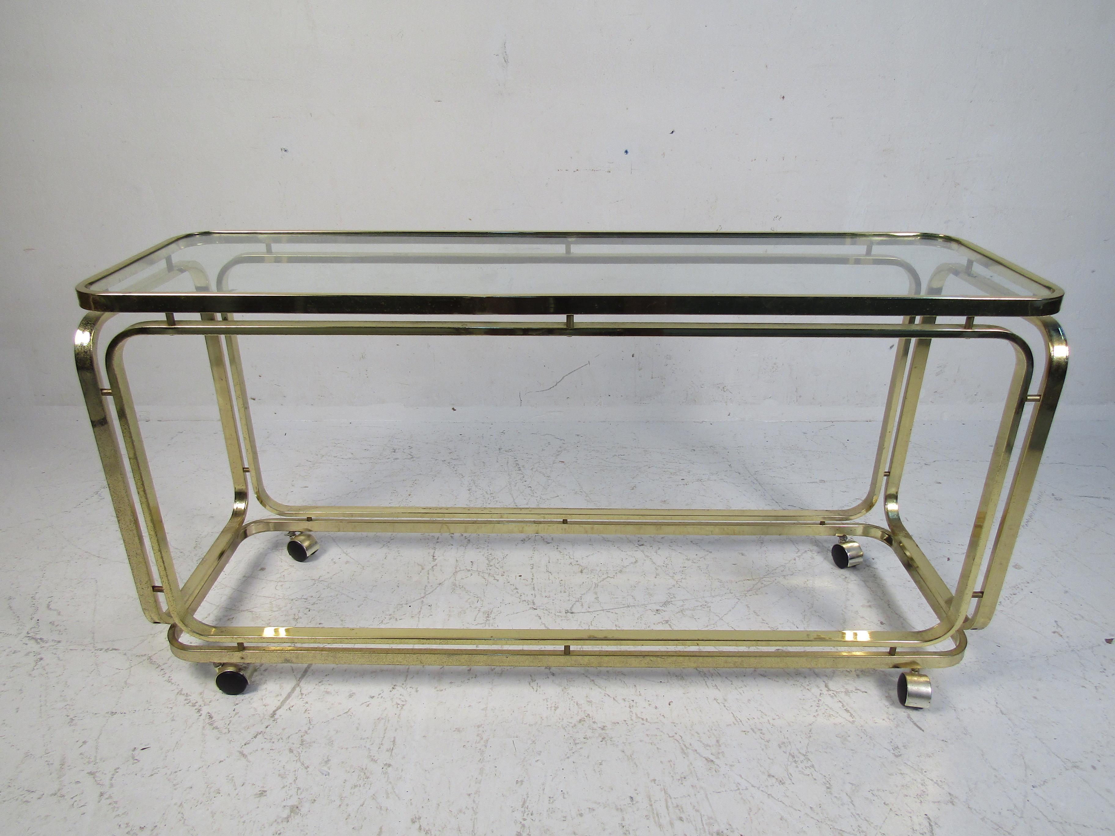 Long rolling cart in polished brass with two shelves. Used as a bar cart or rolling console table.
(Please confirm item location - NY or NJ - with dealer).
  