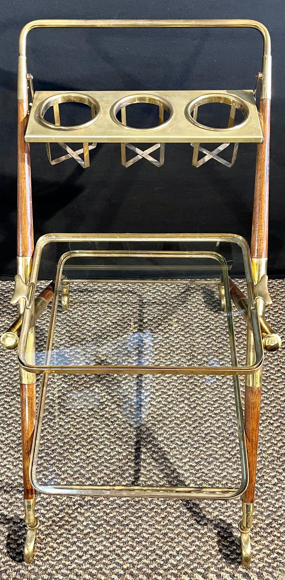 Mid-Century Modern bar cart. Teak and brass bar cart or serving cart with bottle holders and glass holders as well as glass shelving.