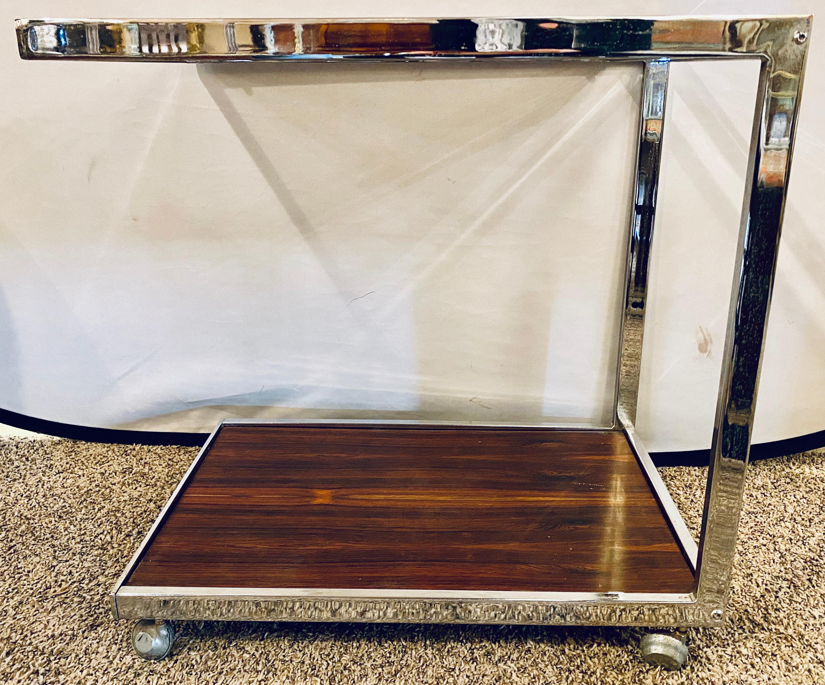 Mid-Century Modern bar or serving cart. Milo Baughman rosewood & chrome on casters. Having a smoked glass top and rosewood base this highly desirable and sweet bar or serving cart is not only love to view but highly functional. One of many pieces by
