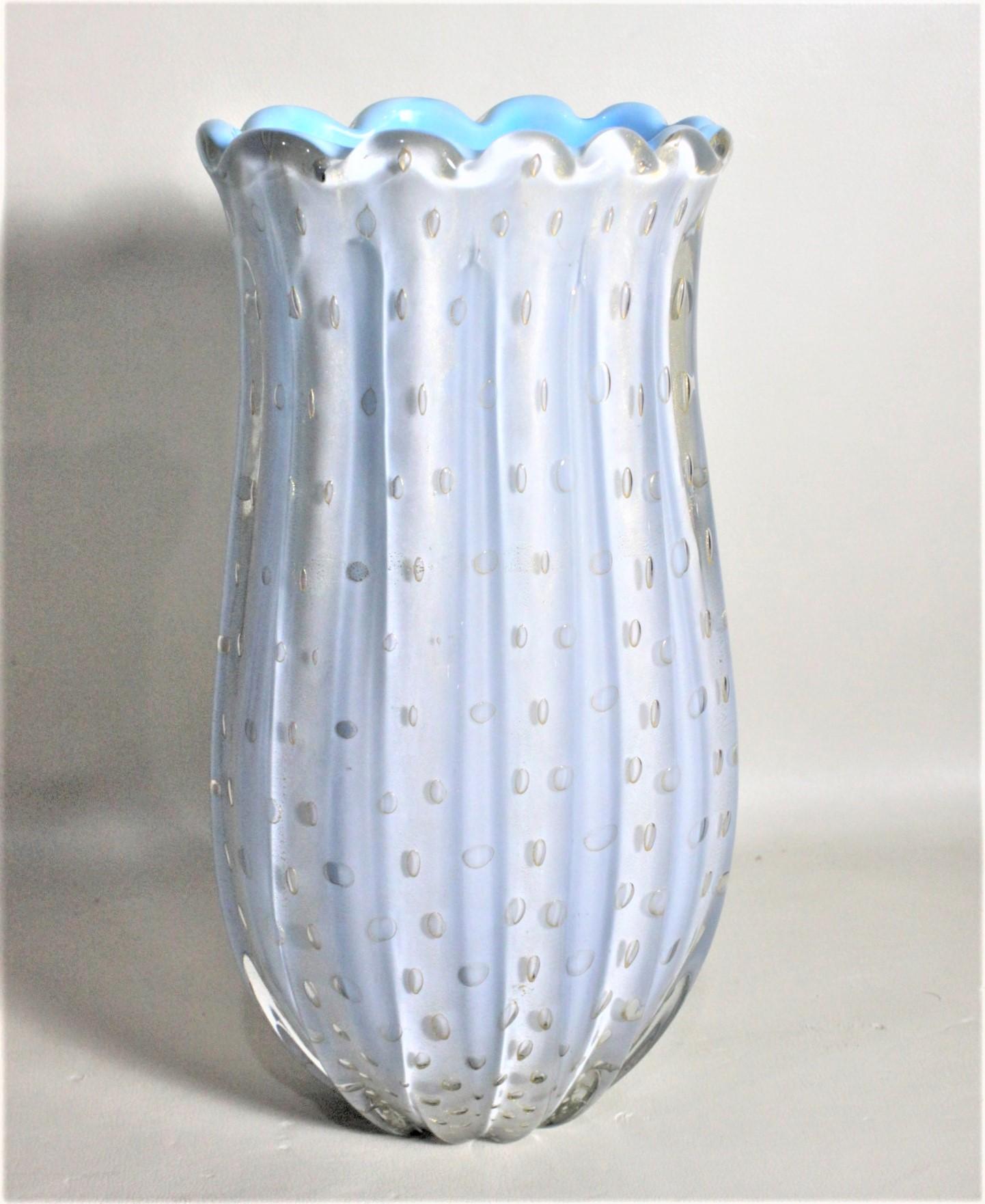 This Murano art glass vase is unsigned, but was most likely done by Angelo Barovier of Italy in circa 1969 in the period Mid-Century Modern style. The vase is a cased white over turquoise glass with ripples around the rim and a cascading controlled