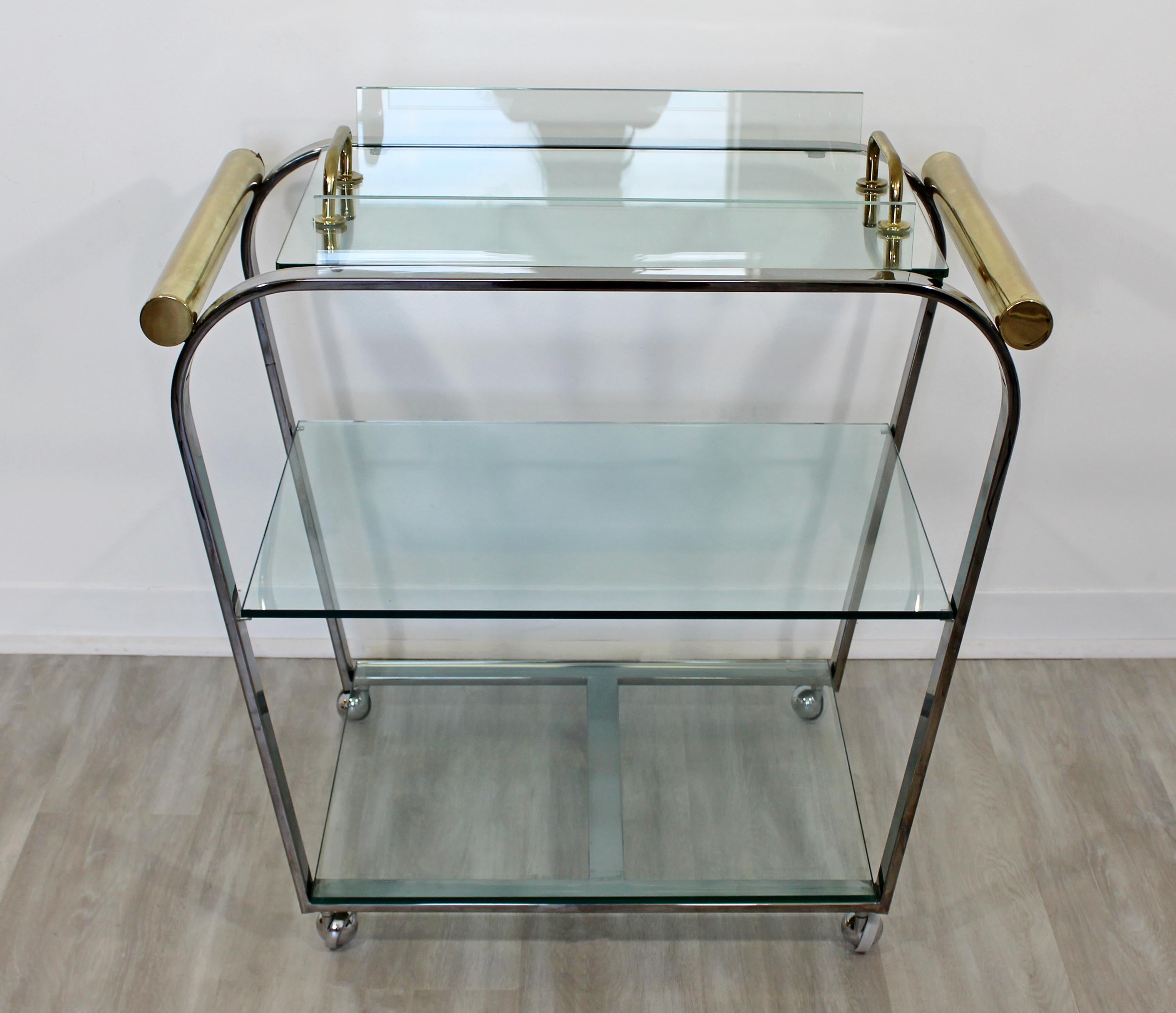 For your consideration is a romantically rounded bar or serving cart, with a removable tray top, made of brass, chrome and glass, for the Design Institute of America, circa 1970s. In very good vintage condition. The dimensions are 33.5