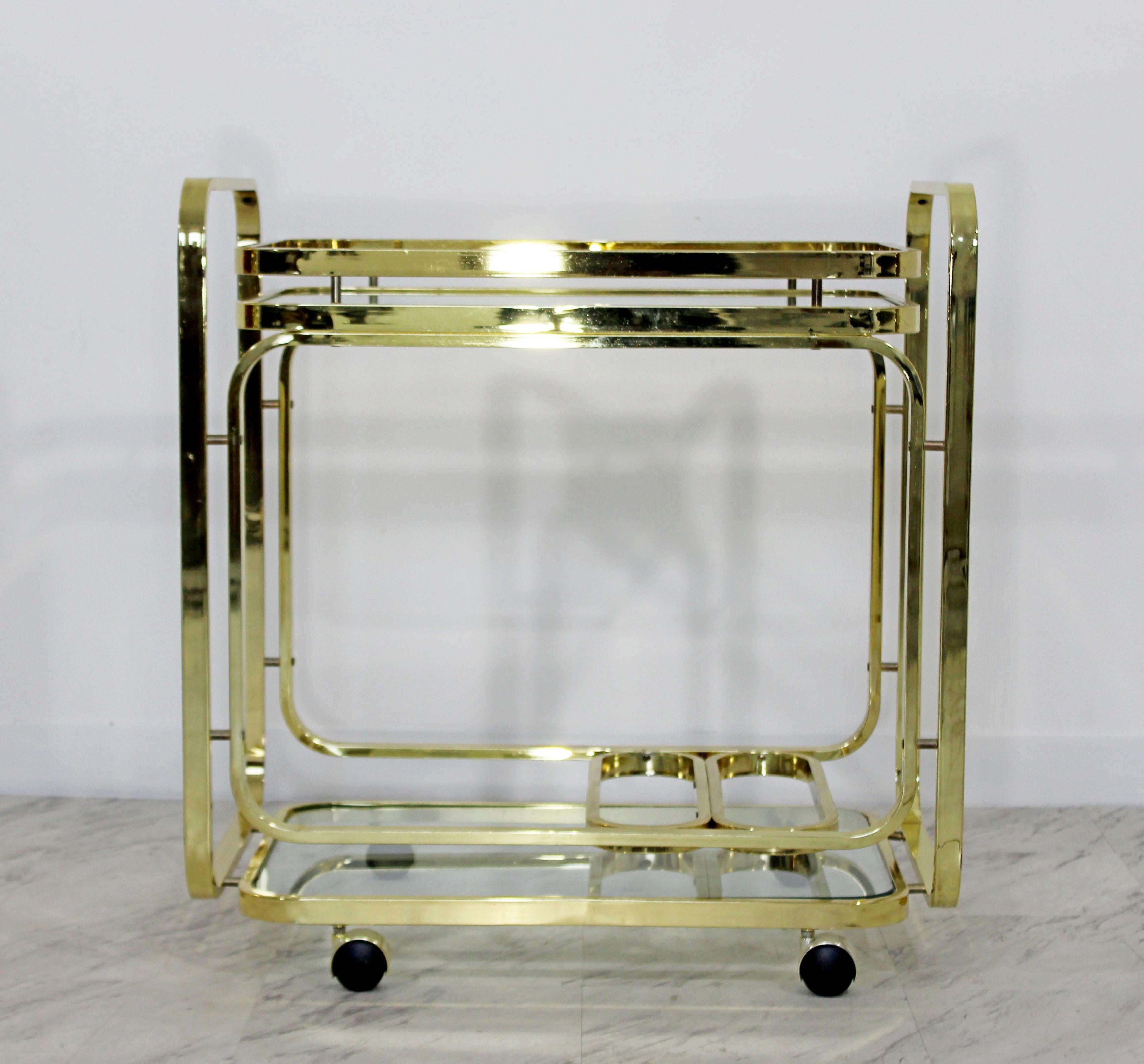 For your consideration is a magnificent, two-tiered, brass and glass, rolling bar or serving cart, by Milo Baughman for the Design Institute of America, circa 1970s. In excellent condition. The dimensions are 29