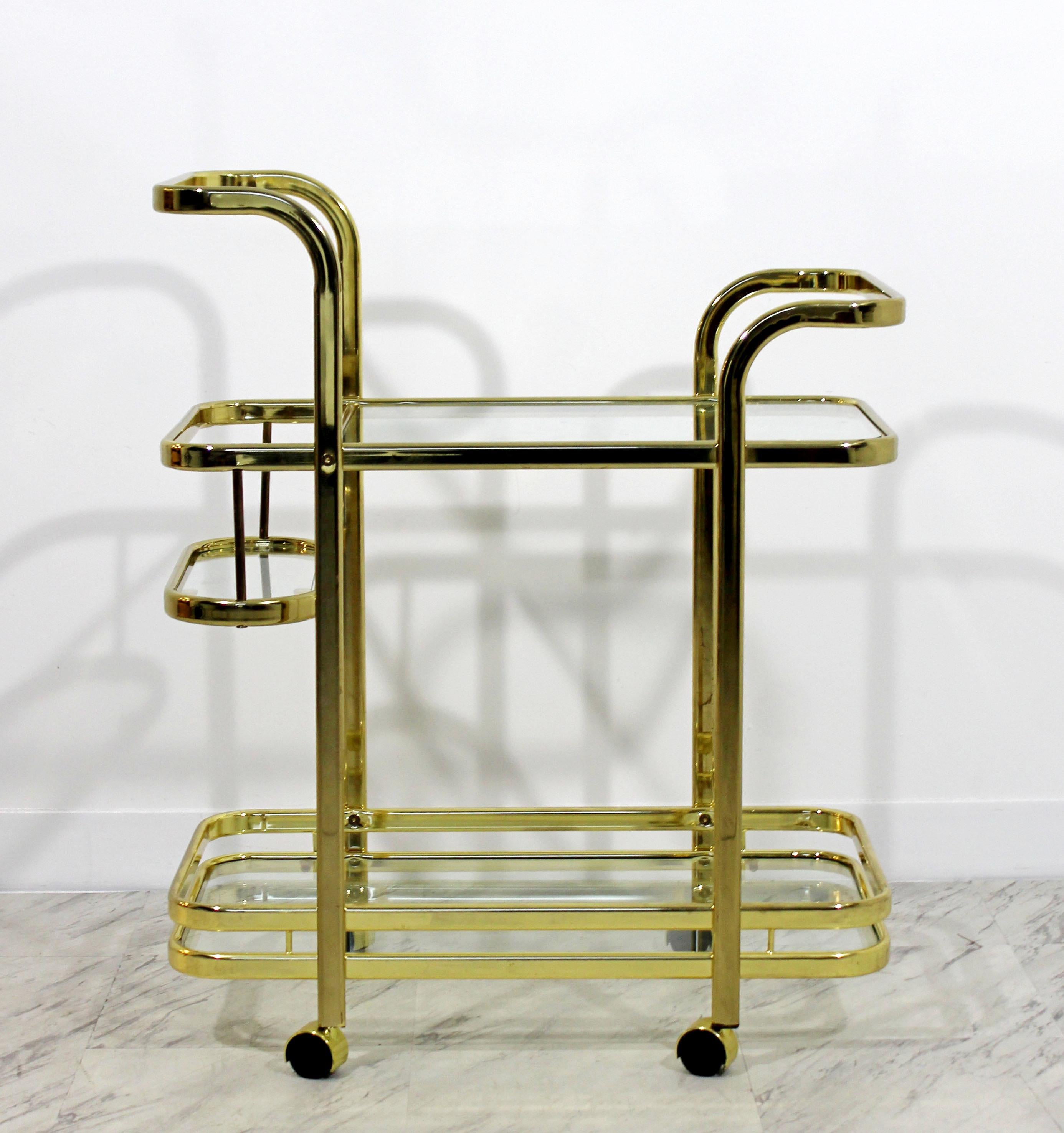 For your consideration is a diminutive, brass bar cart by Milo Baughman for DIA, with three-glass tiered shelves, in the Hollywood Regency style, circa the 1970s. In excellent condition. The dimensions are 26