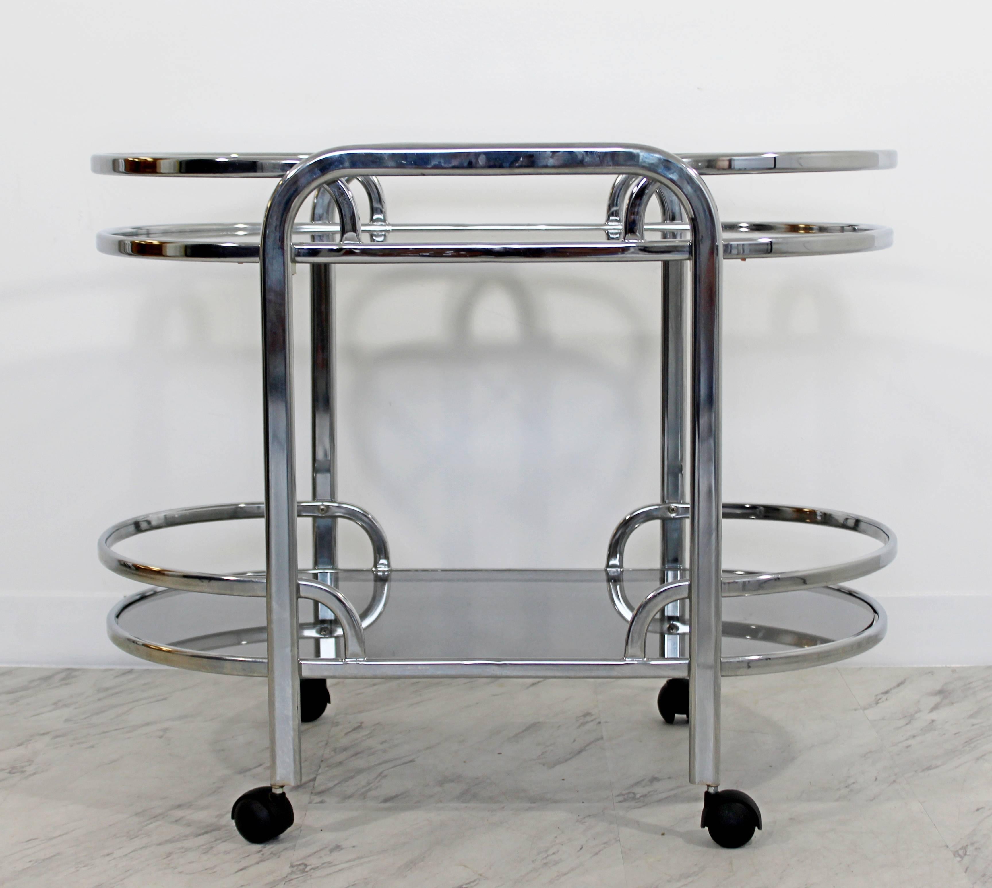 For your consideration is a fabulous, chrome and smoked glass, two-tiered bar or serving cart on casters, with a removable tray table, designed by Milo Baughman for the Design Institute of America, circa the 1970s. In excellent condition. The