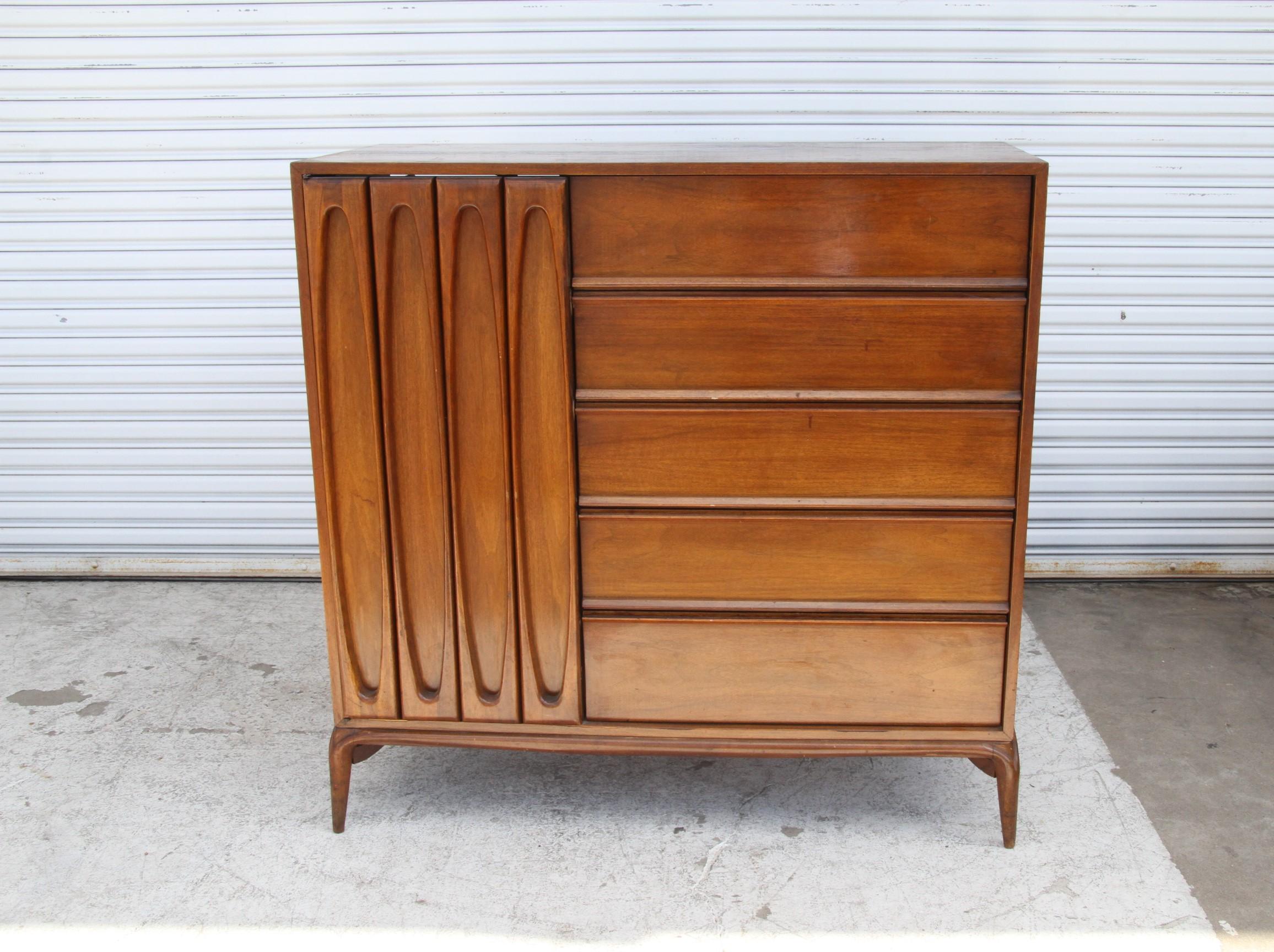 Esta cómoda única de nogal americano presenta una impresionante artesanía vintage, evidente en sus detalles sencillos pero elegantes. Desde las patas cónicas de esquinas redondeadas hasta el frontal esculpido del armario, esta impresionante cómoda