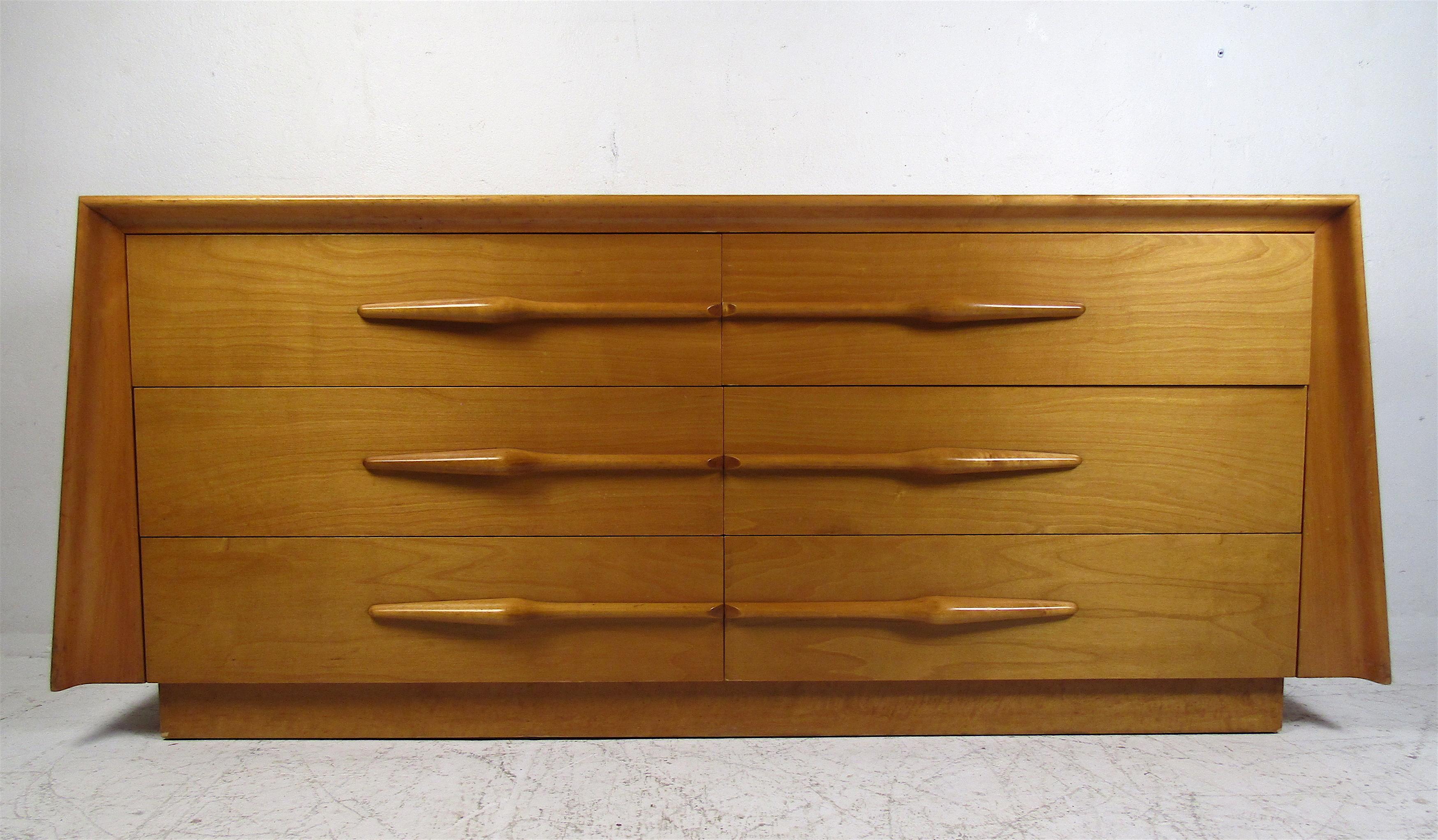 This stunning vintage modern bedroom set includes a dresser and two nightstands. The sculpted drawer pulls and angular design show quality construction. This set offers plenty of room for storage within its many drawers. Sleek case pieces with