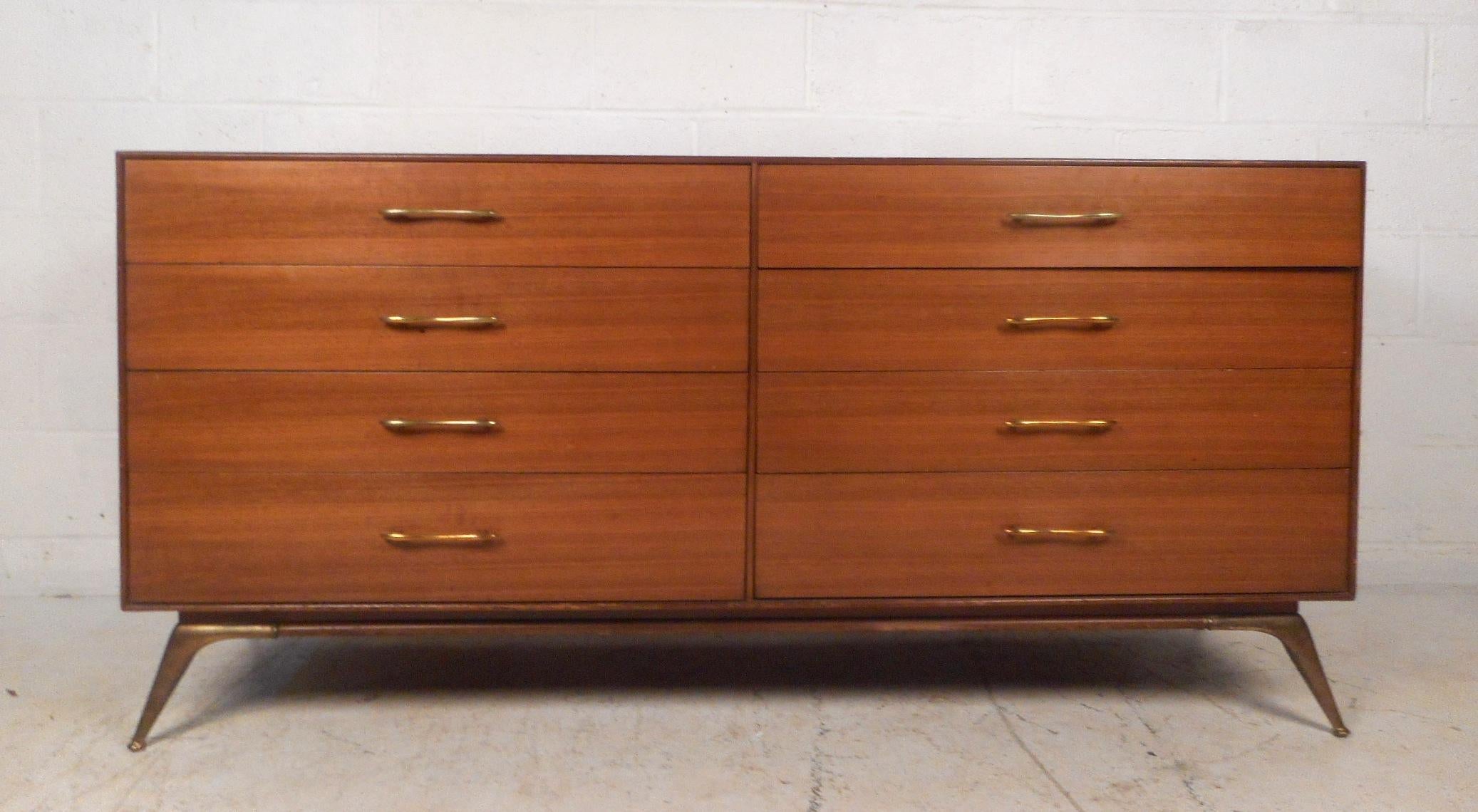 This gorgeous vintage modern pair of dressers feature unusual sculpted brass drawer pulls and splayed brass legs. A sleek design that offers ample storage space within its many drawers. Sturdy construction with clean lines and a rich vintage walnut