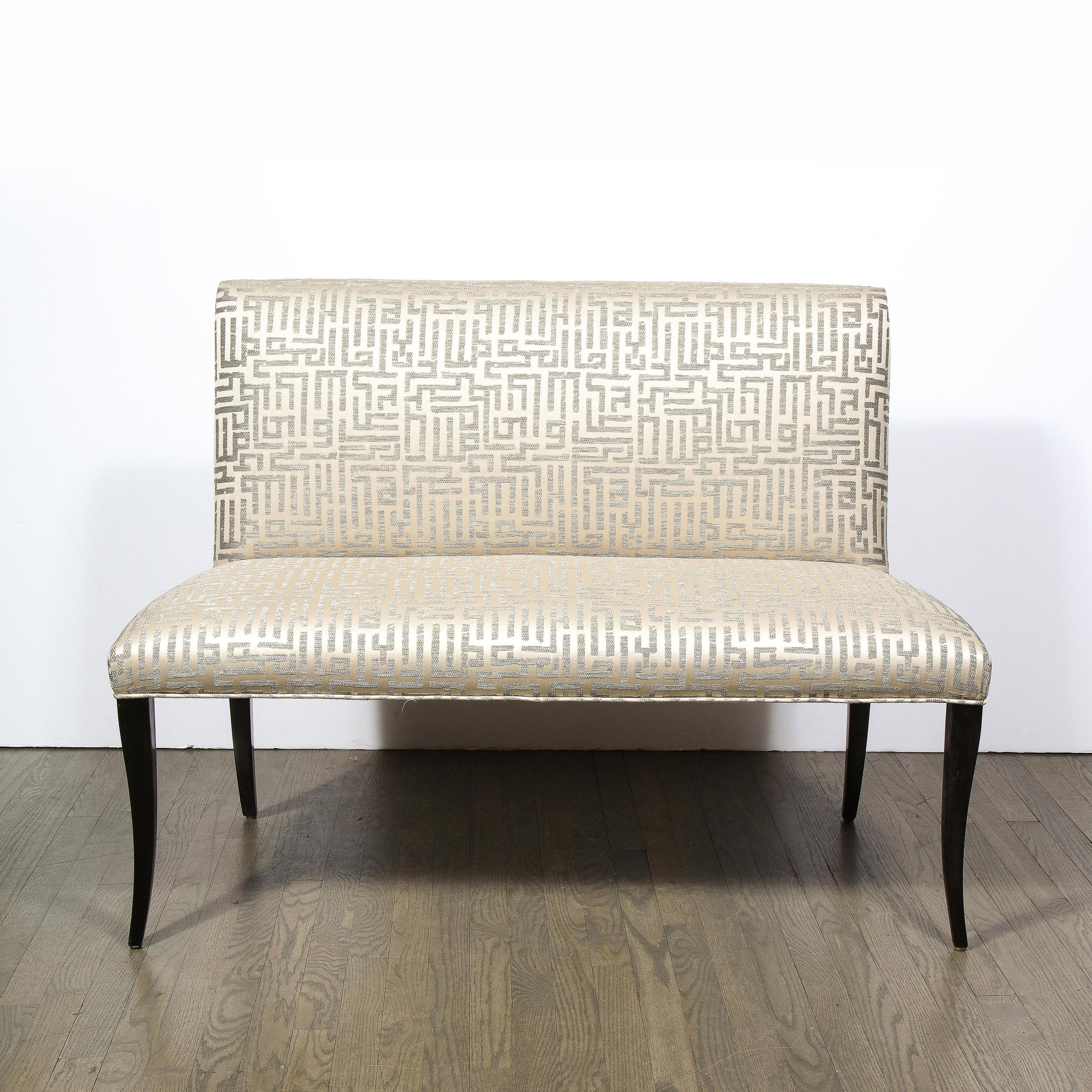 This impeccably styled piece is made from ebonized walnut featuring poised, saber legs and relaxed back. The bench has been newly reupholstered in a gorgeous, Holly Hunt ”Pale Silver” fabric with allover key fret pattern. A fine addition with
