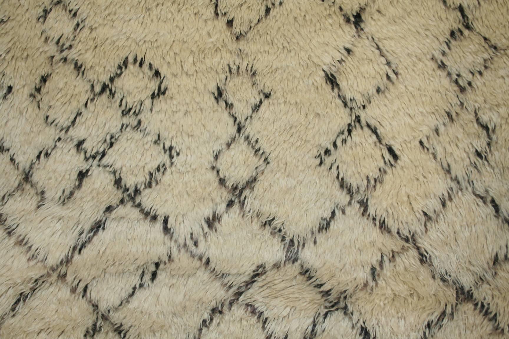 The rugs of the Beni Ouarain tribal confederacy differ from other Berber weavings in that they are woven almost exclusively on an ivory background and decorated with abstract geometric motifs in undyed natural brown/black wool. The pattern is