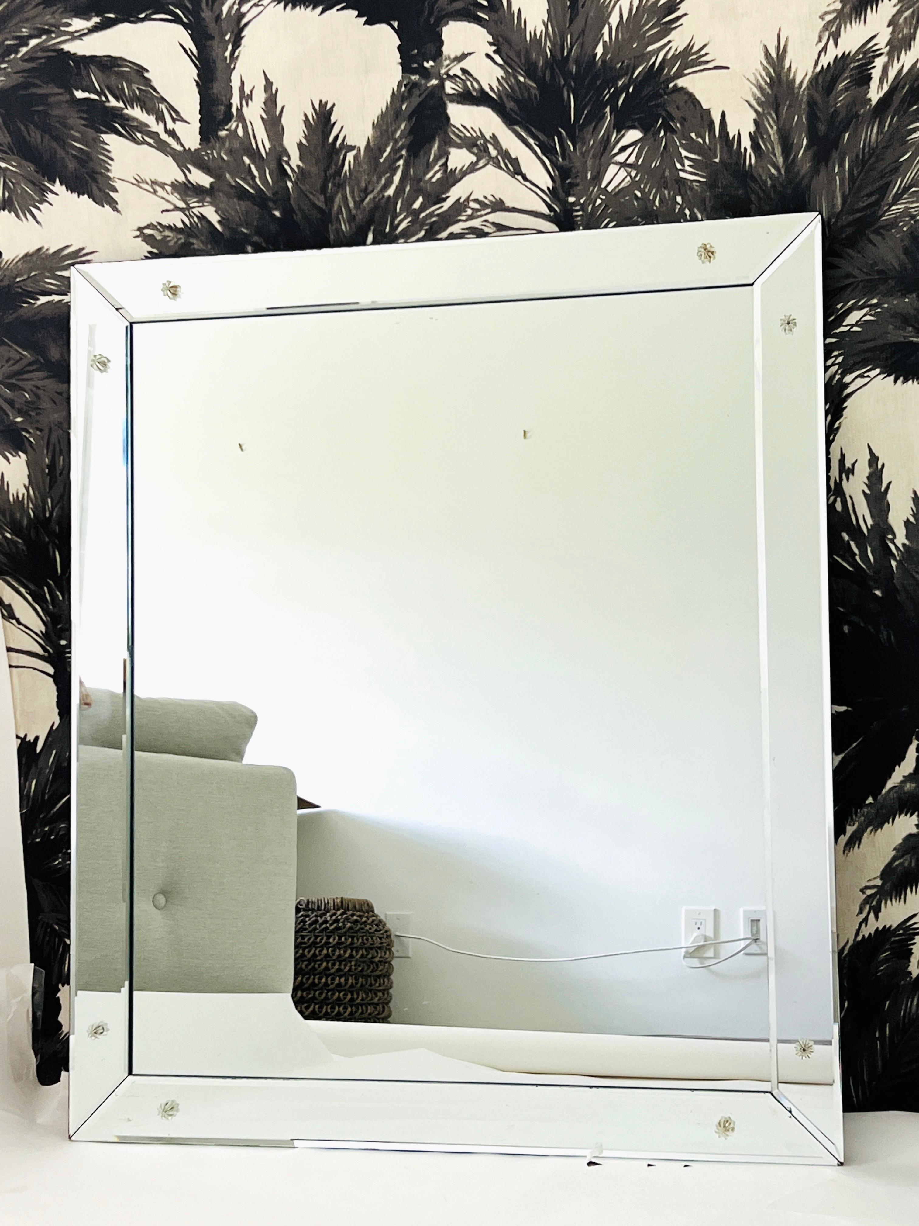 Miroir moderne du milieu du siècle avec des bords biseautés et des rosettes en verre. La simplicité de ce miroir vintage fait tout son charme. L'échelle parfaite pour une entrée ou une salle d'eau, mais son design épuré lui permet de s'intégrer