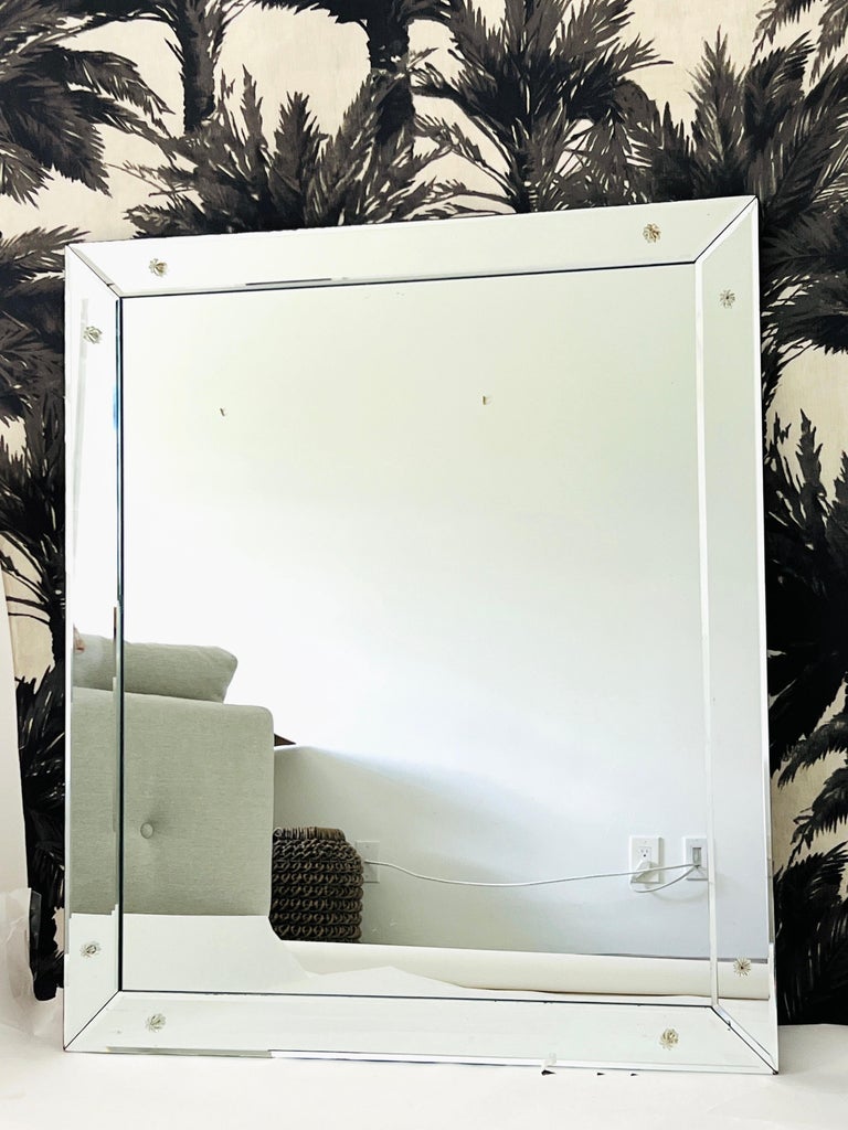Mid-Century Modern mirror featuring beveled borders and fitted with glass rosette accents. The simplicity of this vintage mirror is its allure. Perfect scale for an entry way or a powder room, but its clean streamline design makes it easy for this