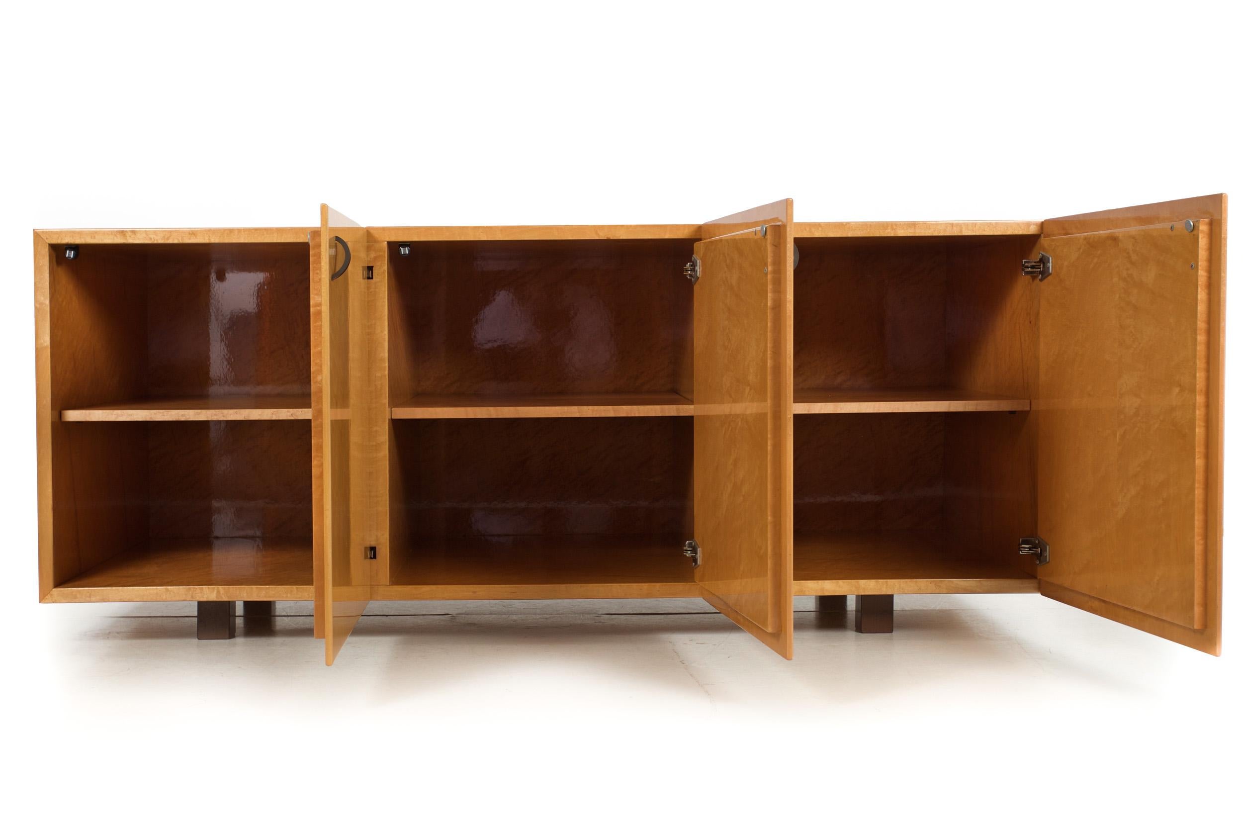 A delightful three-door credenza designed by Giovanni Offredi for Saporiti entirely in birdseye-maple veneered surfaces, it is a brilliant piece that absolutely glows under the shimmering acrylic varnish surface throughout. The doors are set with