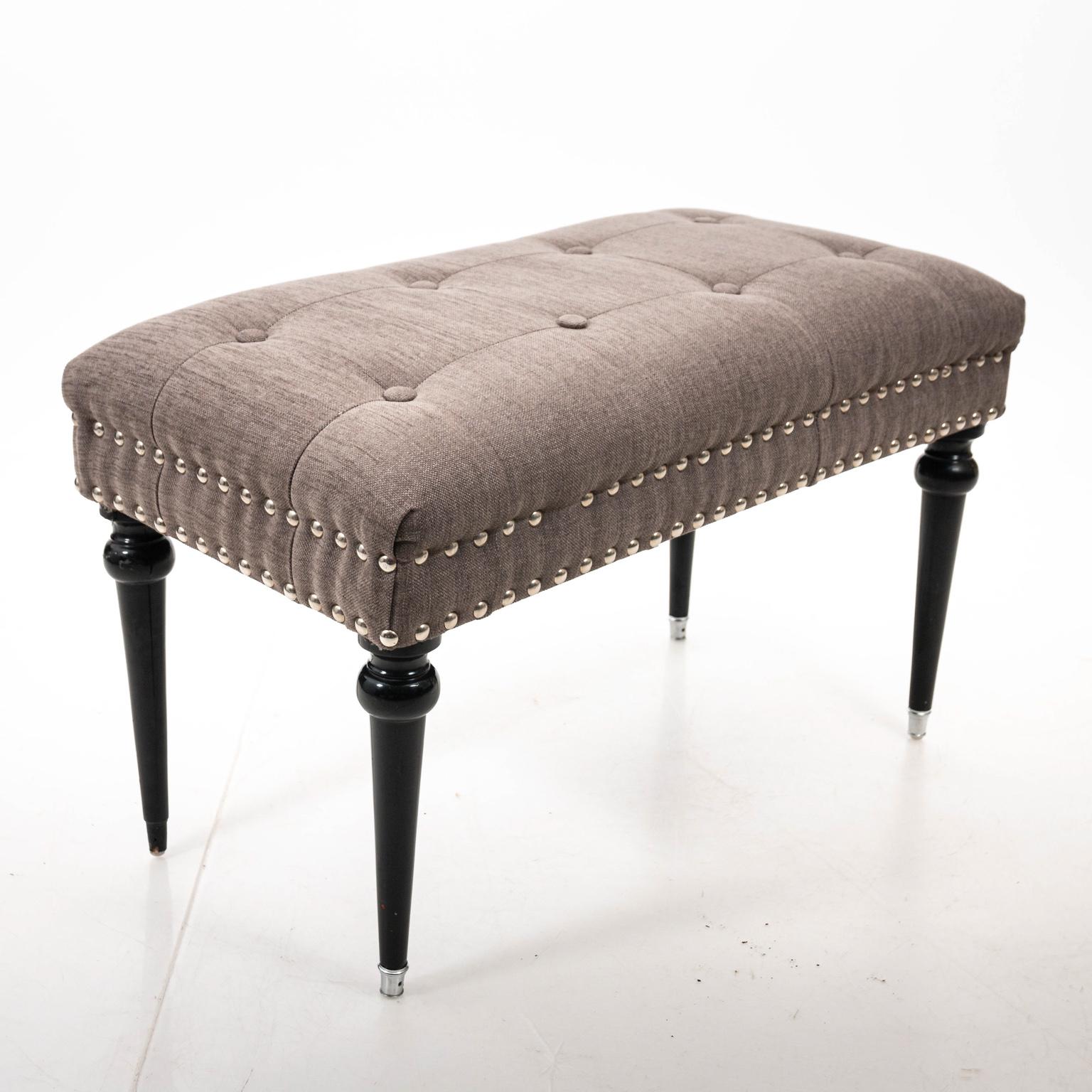 Modern black lacquered bench or stool with upholstered seat in heavy grey cotton blend, circa mid-20th century. The piece also features a tufted seat with nail head trim. Please note of wear consistent with age including minor losses with one