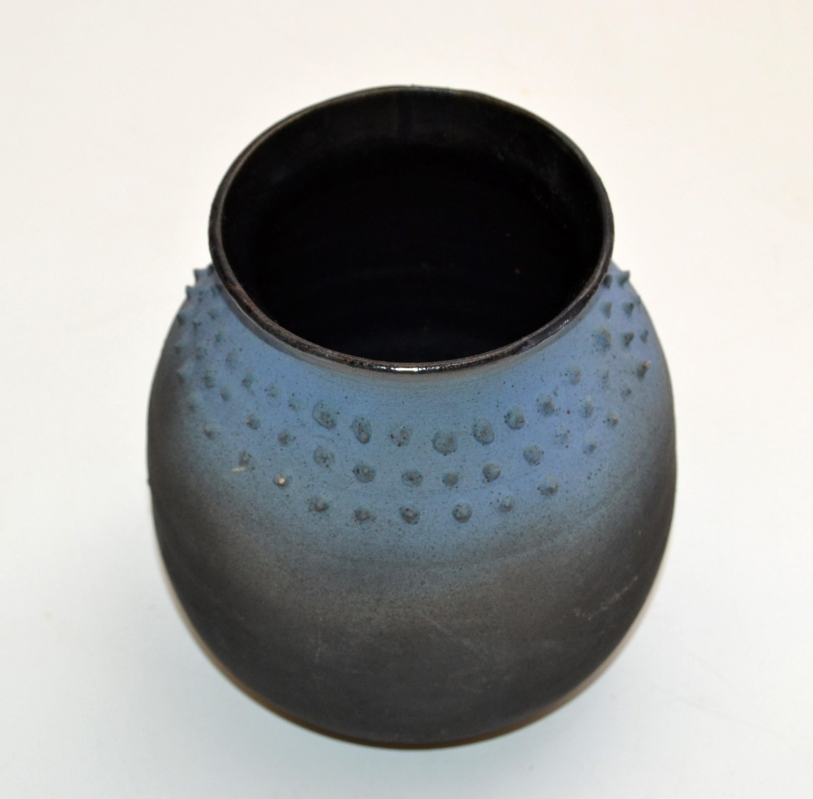 Vase ou récipient Raku américain de style moderne du milieu du siècle, émaillé à l'intérieur, de couleur bleue et noire, fait à la main.
La poterie de Studio Art Pottery est à deux textures avec des pointes sur le tiers supérieur du vase.

 