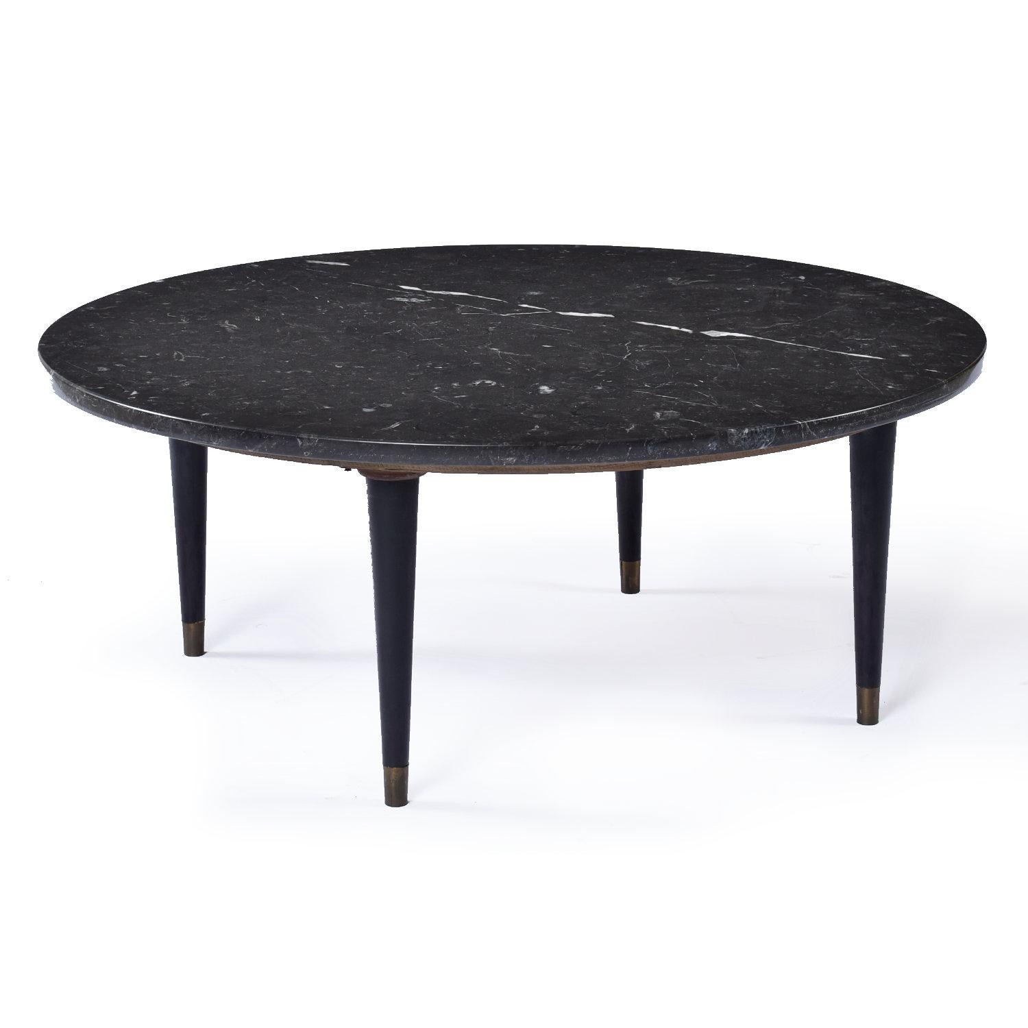 Handsome black marble Mid-Century Modern coffee table. The round coffee table is not quite pure black. The marble is deep charcoal gray. The circular coffee table is supported by four satin black enamel legs. The legs are pencil turned with the