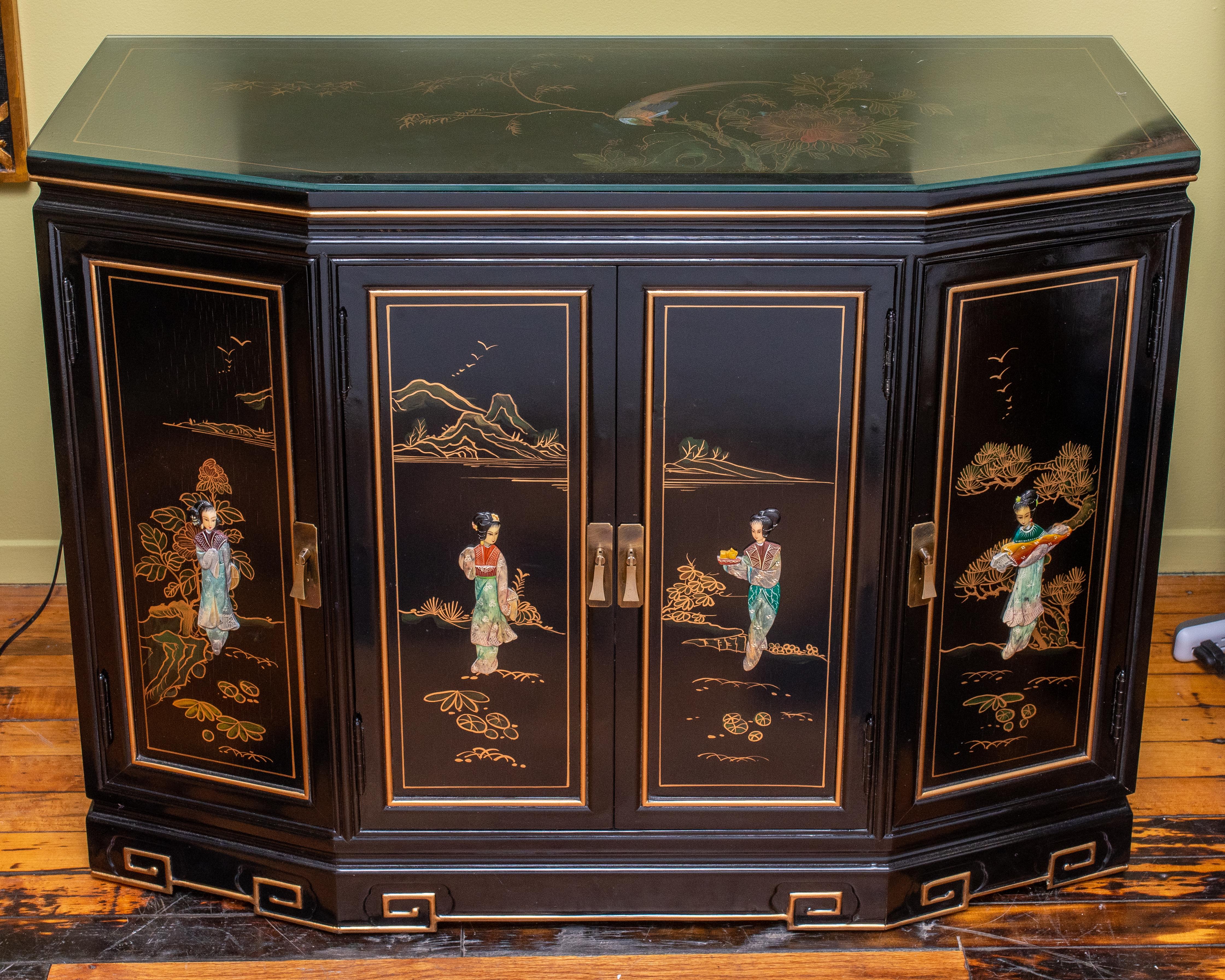 Mid-Century Modern black Chinese Chinoiserie credenza. Hand painted on the top and the sides. Front has figure with inlaid stones. Made in 1970s. Drawer in middle section - 1 shelf each side. There is a 1.4