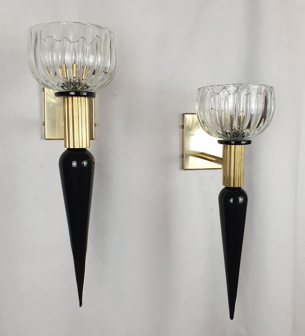 Pair of elongated or Torchiere vintage Murano glass sconces, Venini style, Italy 1960s.
The Mid-Century Modern wall lights are made of hand blown black and clear Murano glass elements with brass mounts.
The neoclassical pair of sconces have one