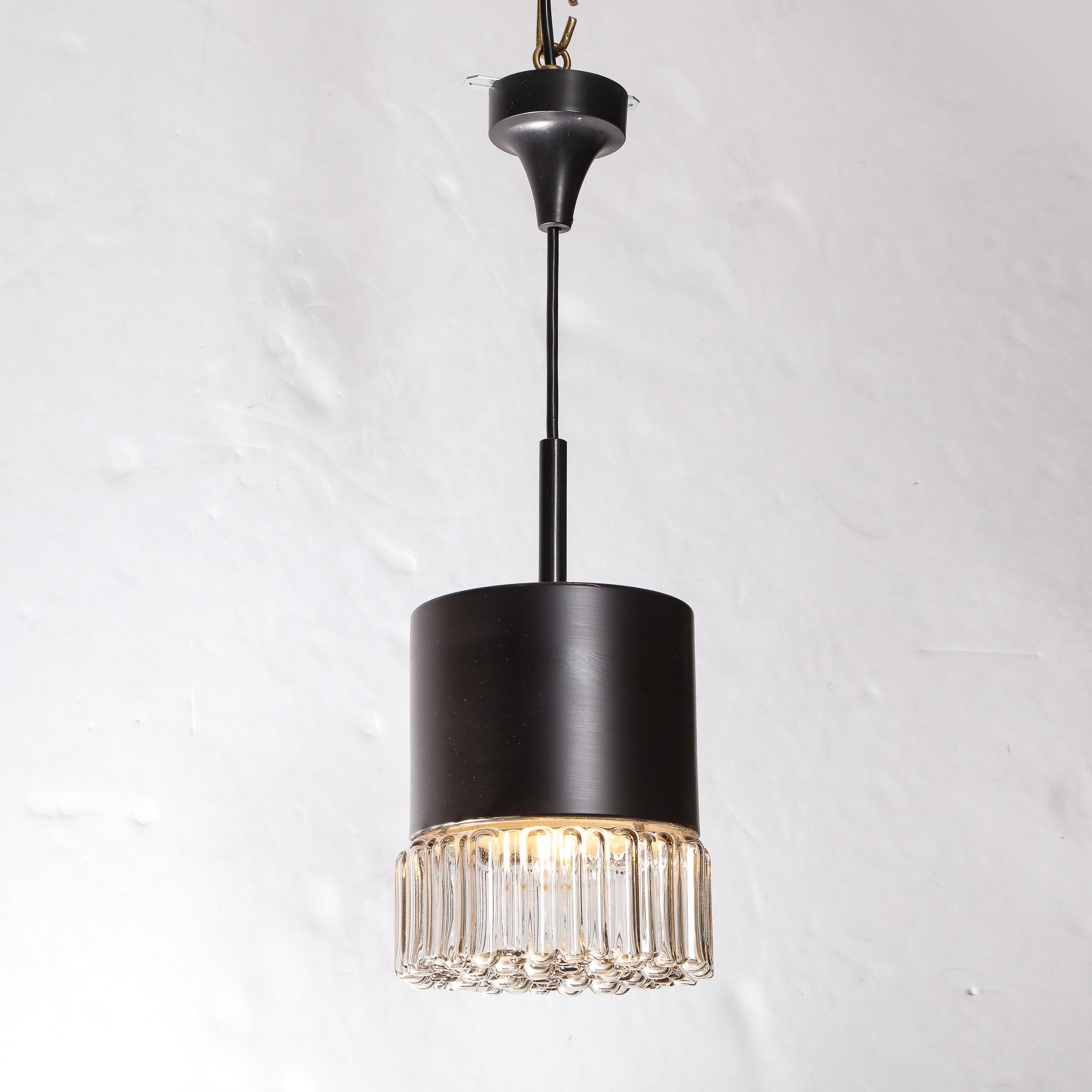 This stunning Mid-Century Modern pendant was realized by the esteemed lighting atelier of Glashütte Limburgh in Germany, circa 1950. It features a cylindrical body and domed canopy in black enamel with a highly textural translucent 