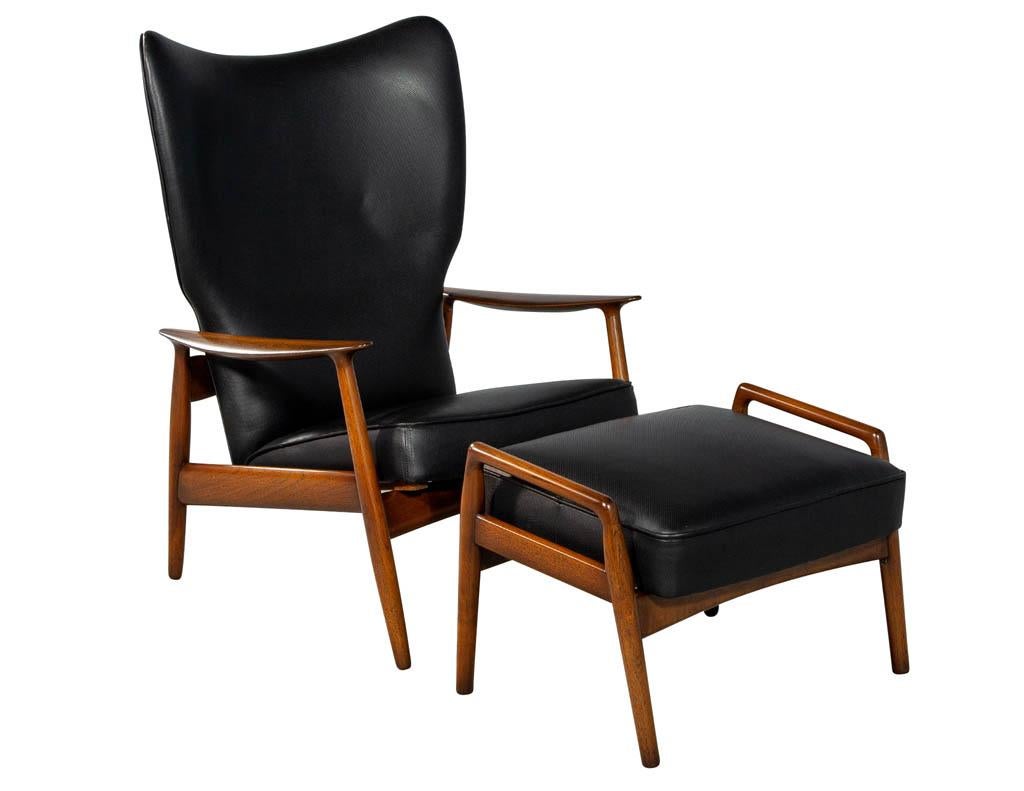 Beautifully restored by our master craftsmen, upholstered in a designer perforated black leather, finished in a rich hand rubbed finish with an accented grain detail. Chair back reclines for extra comfort. Includes matching ottoman.

Measures: