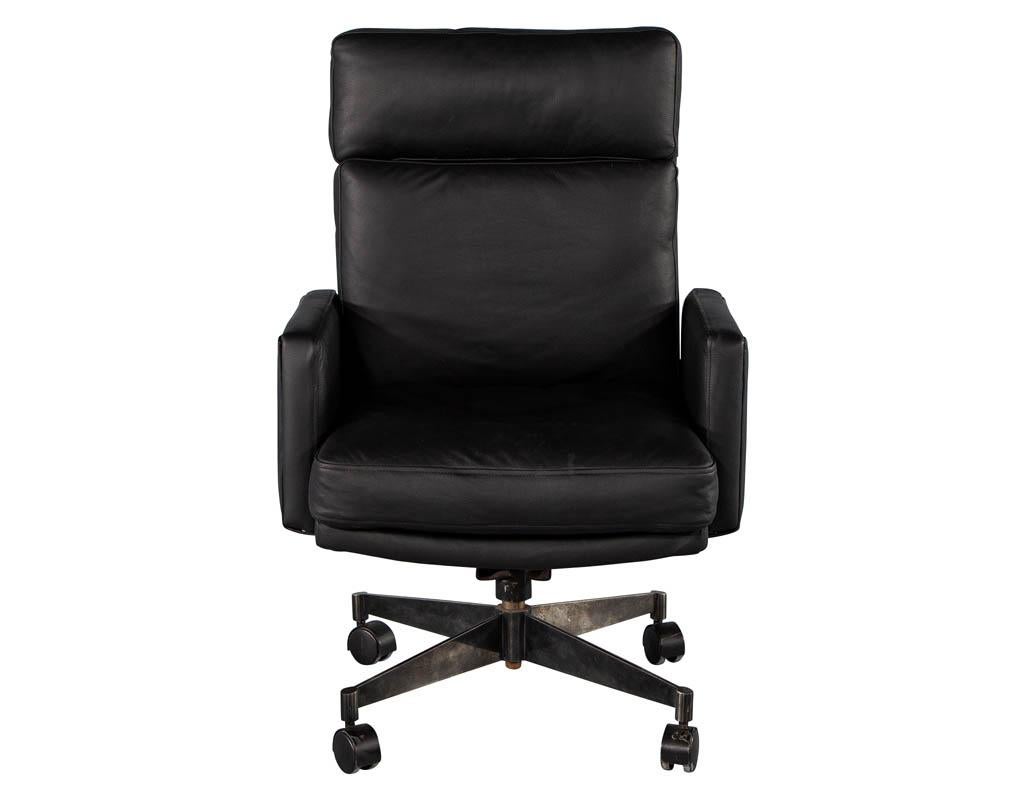 Mid-Century Modern black leather office chair. America, circa 1970s. Restored in all new Italian leather with unique perforated texture. Thick seat and back cushions for comfort. Completed with unique patinaed metal base on castors. Chair is not