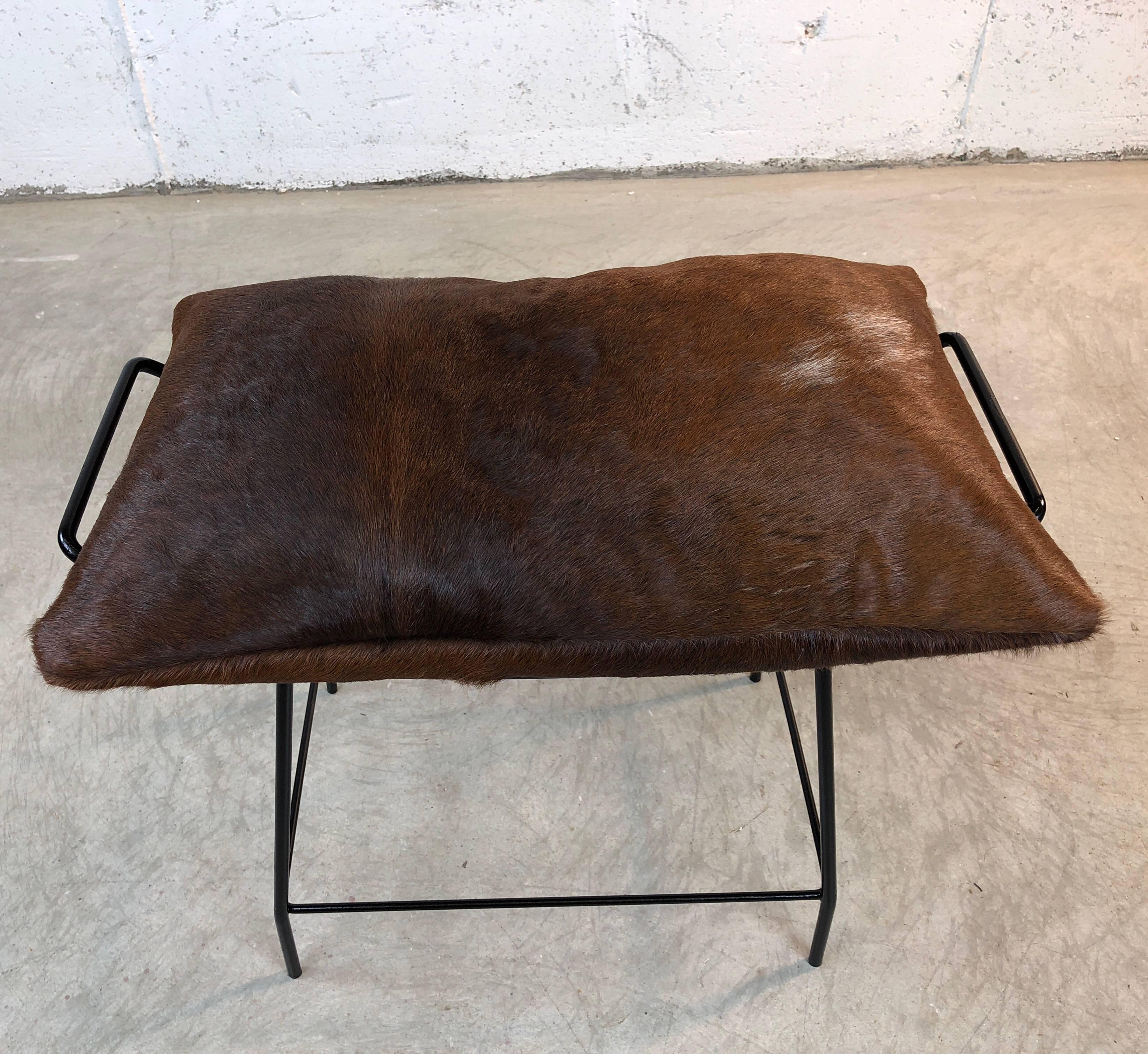 Mid-Century Modern black painted metal vanity stool with brown cowhide pillow. The vanity has handles and a mesh base and is newly refinished. The pillow is new cowhide. No marks. 

Measures: 21, 11, 18.