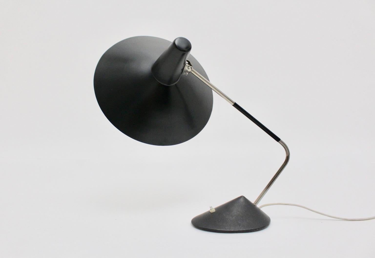 Mid Century Modern  vintage table lamp by Stilnovo made from black metal and nickel-plated metal.
A charming table lamp or desk lamp from the 1950s by Stilnovo with a wonderful shape and style.
The round shaped lamp shade reminds on a witch hat with
