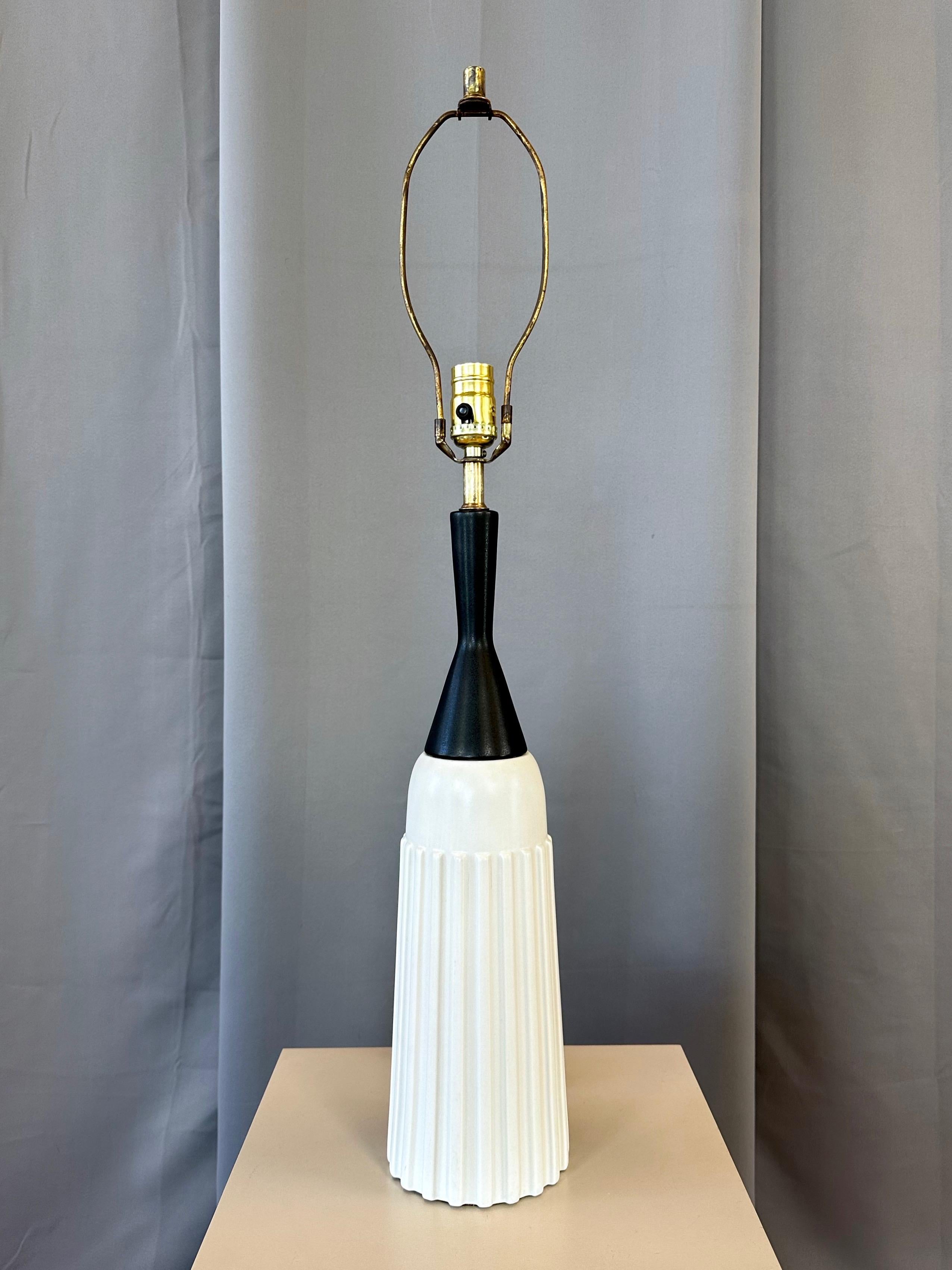 A very dapper and uncommon 1950s bottle-shaped ceramic table lamp with white ribbed body and black tapered neck.

Handsome lines, perfect proportions, and a Truman Capote-approved black and white color scheme call to mind a natty bowtie and tuxedo