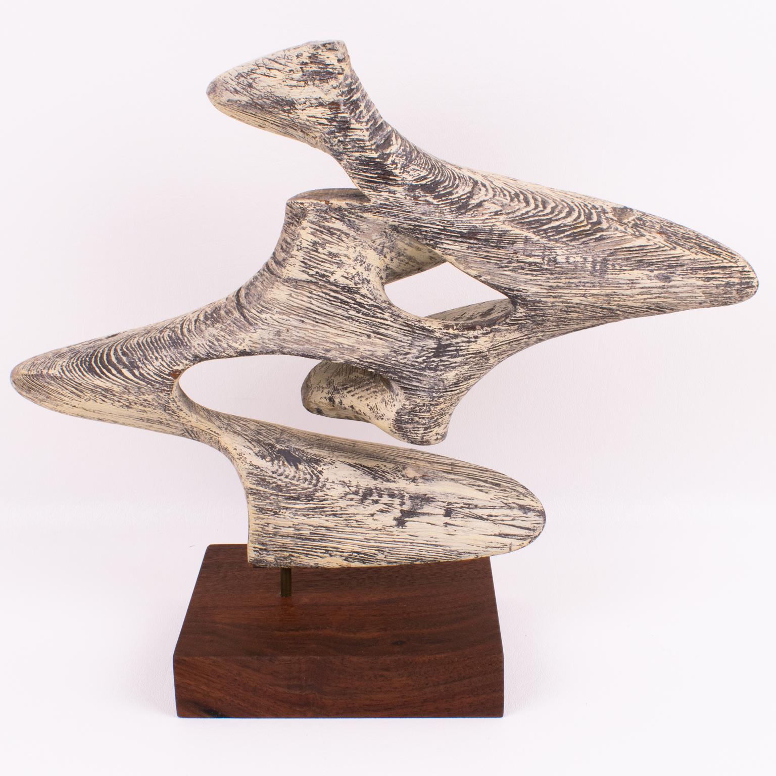This elegant Mid-Century Modern wooden abstract sculpture was hand-crafted in the 1970s. This finely carved stylized free-form sculpture is made of bleached wood, with a very versatile design different from every angle. The base is made of another
