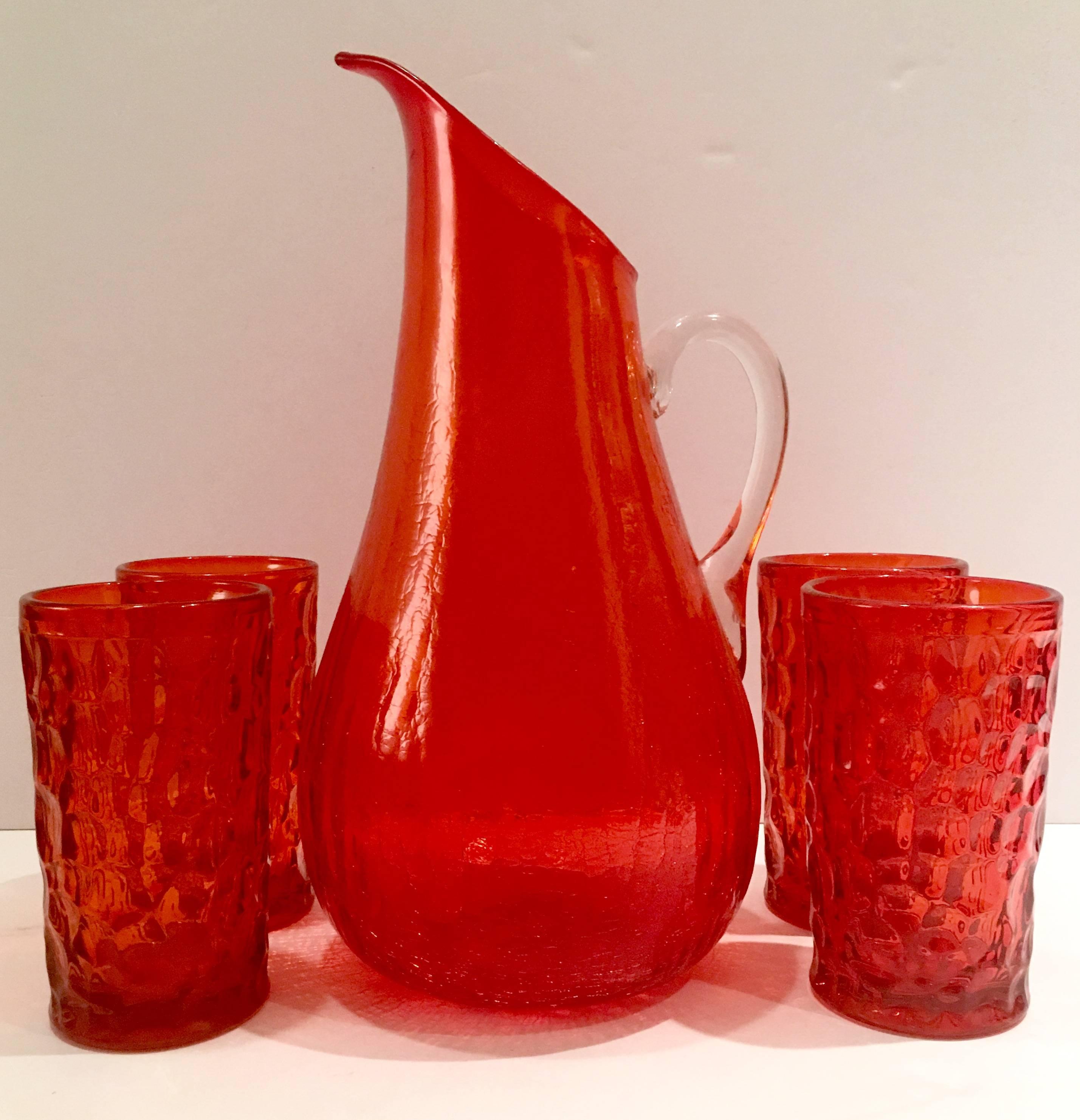 Mid-Century Modern Set Of Bright Tangerine Four Blenko Glass Tall Textured Tumbler Glasses and Blenko style Spouted & Handled Beverage Pitcher. This set of five blown glass pieces includes, 4 tumblers and one  clear applied handle bright orange
