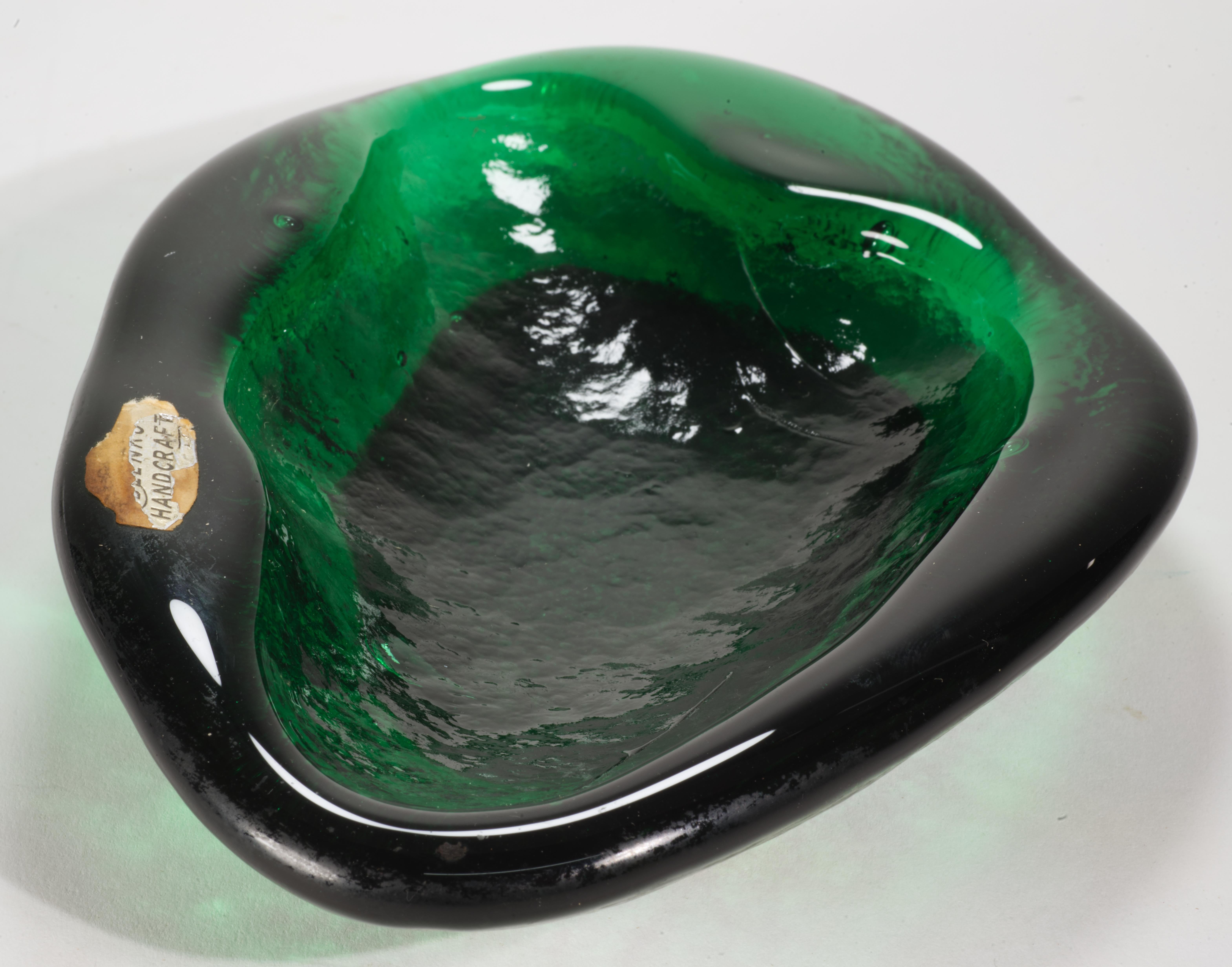  Vintage Amoeba Freeform glass ashtray, bowl, or dish features asymmetrical, Organic Modern shape with thick emerald colored glass sides and lightly textured inner and outer surfaces. The texture is exaggerated by a few bubbles inside the glass and